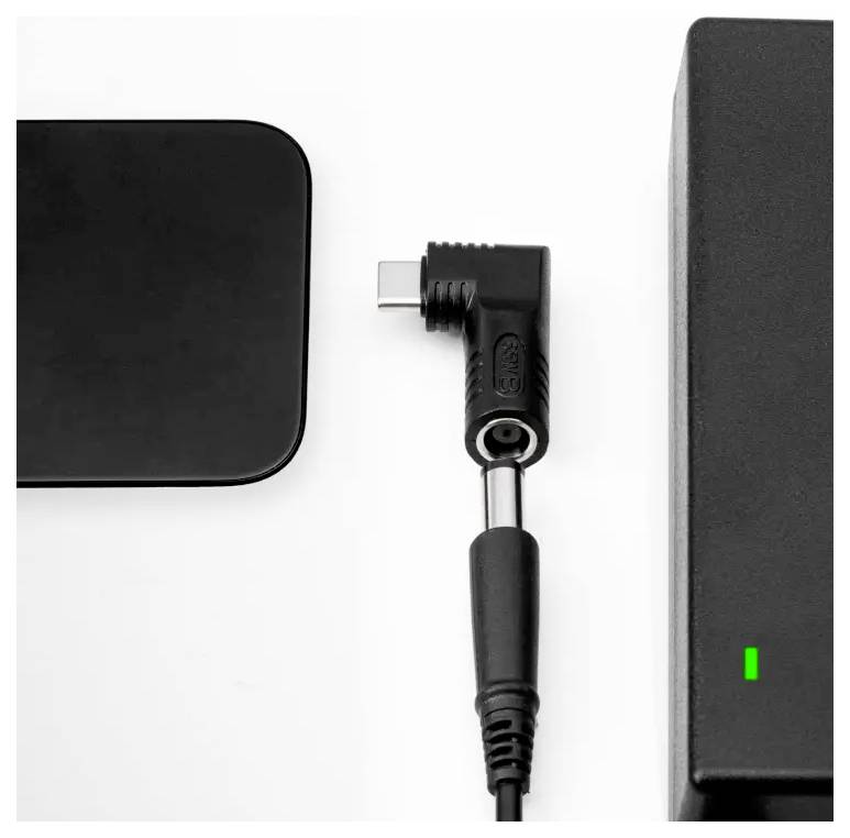 Un chargeur noir avec une lumière verte à côté d'un connecteur hors tension sur fond blanc.