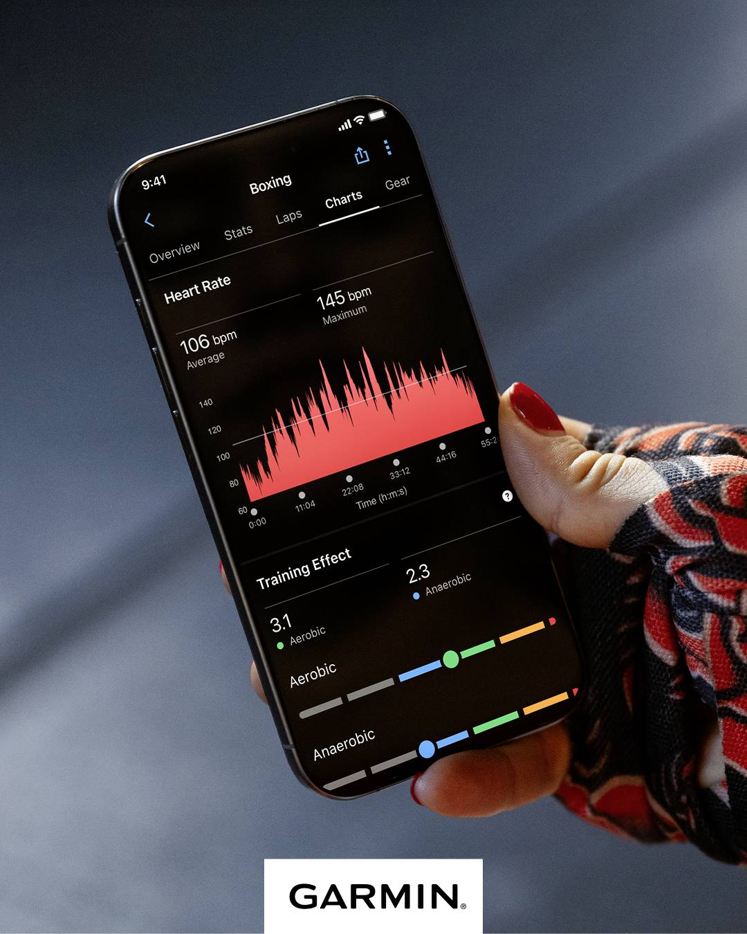 Personne tenant un smartphone affichant une application Garmin. L'écran montre des graphiques de fréquence cardiaque et d'effets d'entraînement pour la boxe.