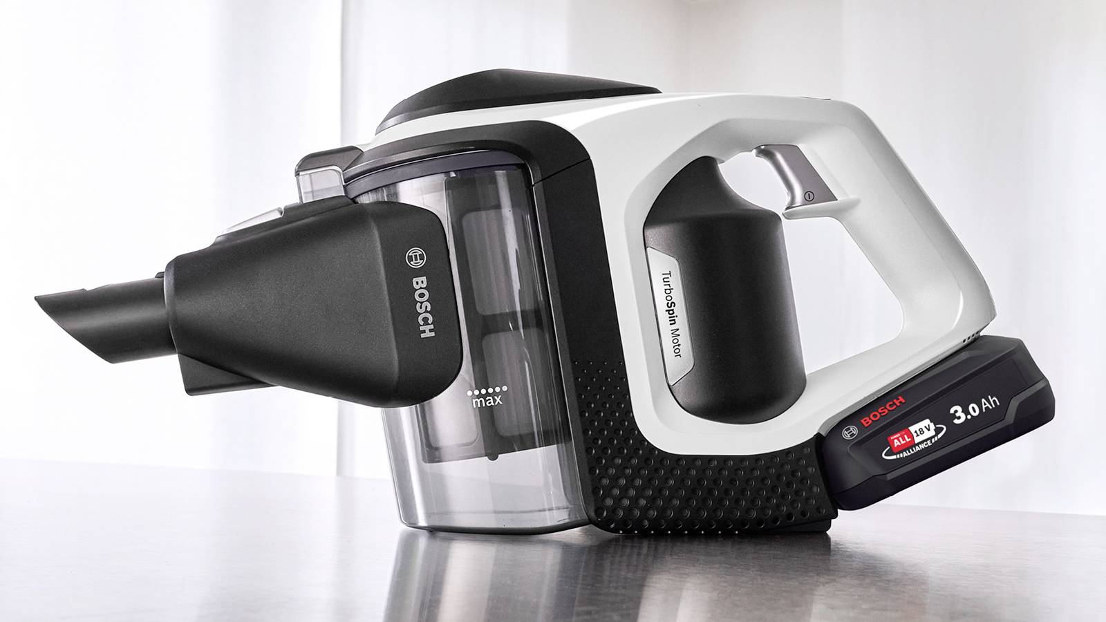 Un aspirateur à main avec une batterie amovible, présentant un design élégant et la marque « Bosch », posé sur une surface réfléchissante.