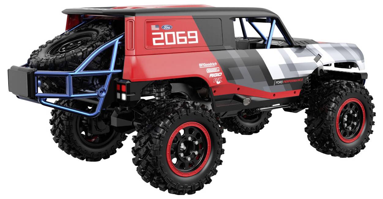 Véhicule tout-terrain avec de grandes roues et une structure de protection, arborant le numéro '2069' sur sa carrosserie rouge et grise, vu de l'arrière et du côté.