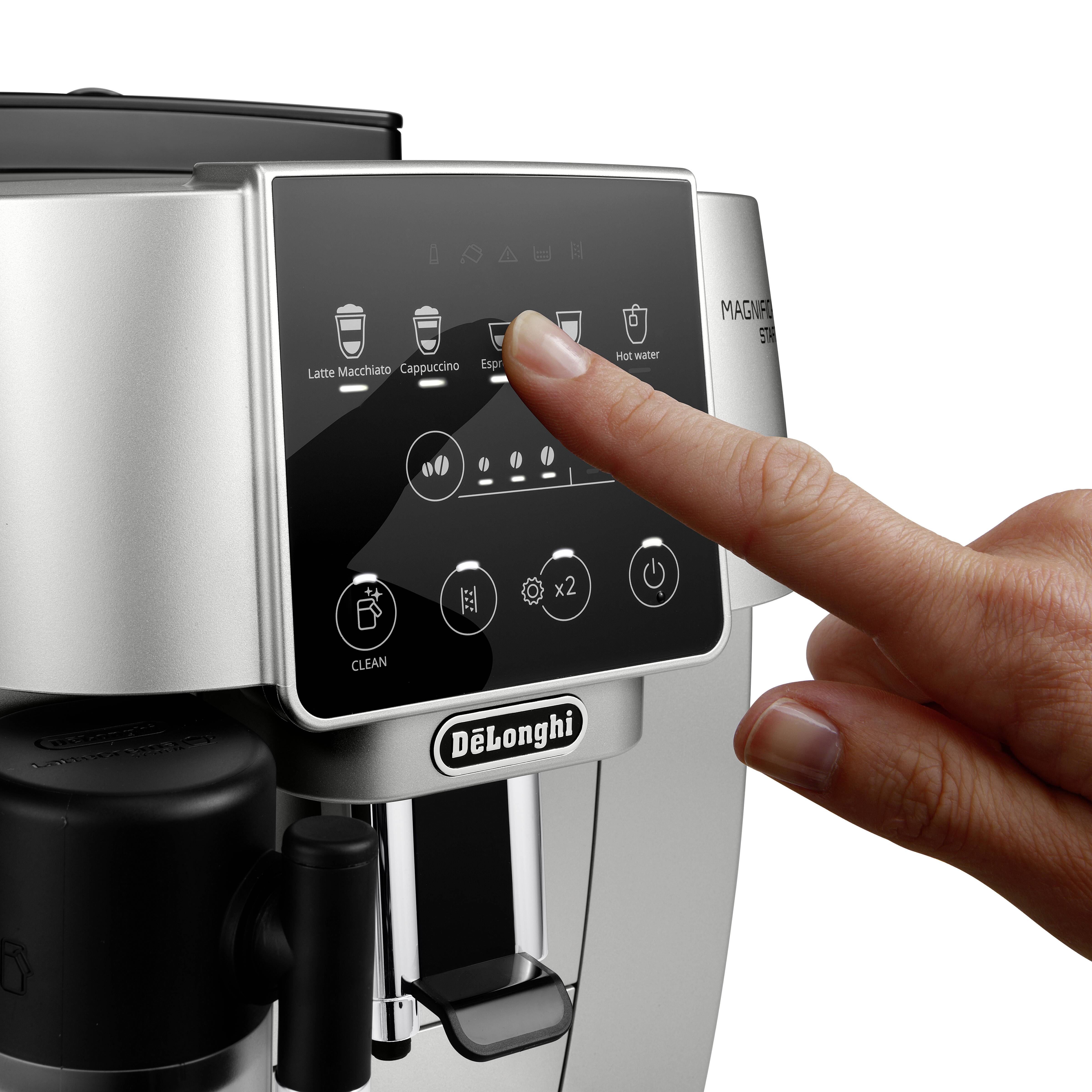 Un doigt effleure l'écran digital d'une machine à café DeLonghi Magnifica, mettant en surbrillance des options comme Espresso et Eau chaude.