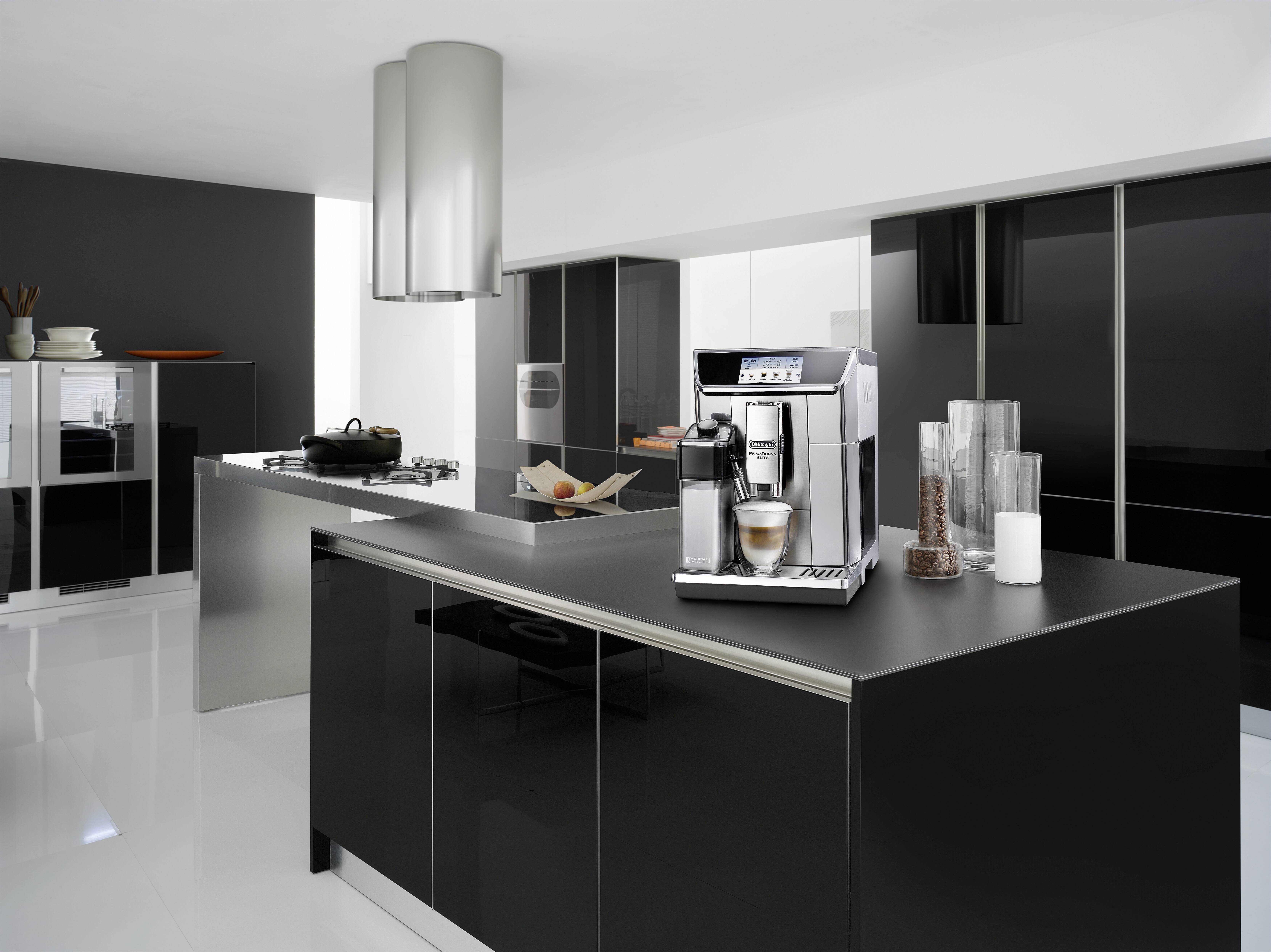 Une cuisine moderne avec des armoires noires épurées et un îlot central. Une machine à café est placée bien en vue sur le plan de travail.