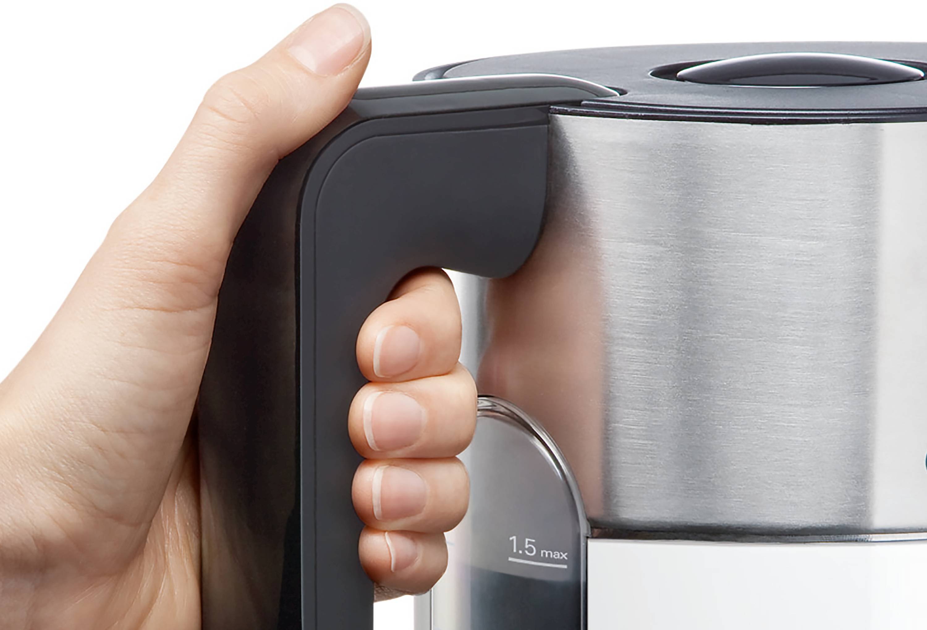 Une main saisit la poignée d'une bouilloire électrique en acier inoxydable, avec un indicateur de niveau d'eau marqué à « 1,5 max ».