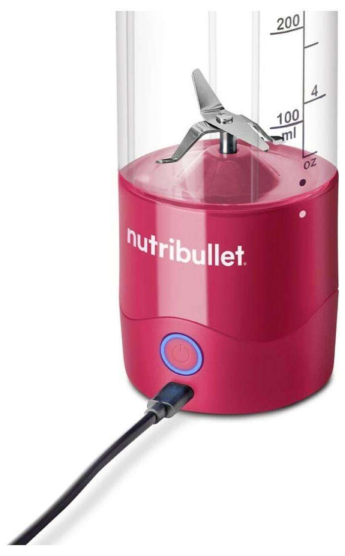 Un mixeur Nutribullet rouge avec un bouton marche-arrêt visible et une échelle de mesure allant jusqu'à 200 ml sur le côté. Le mixeur est branché.