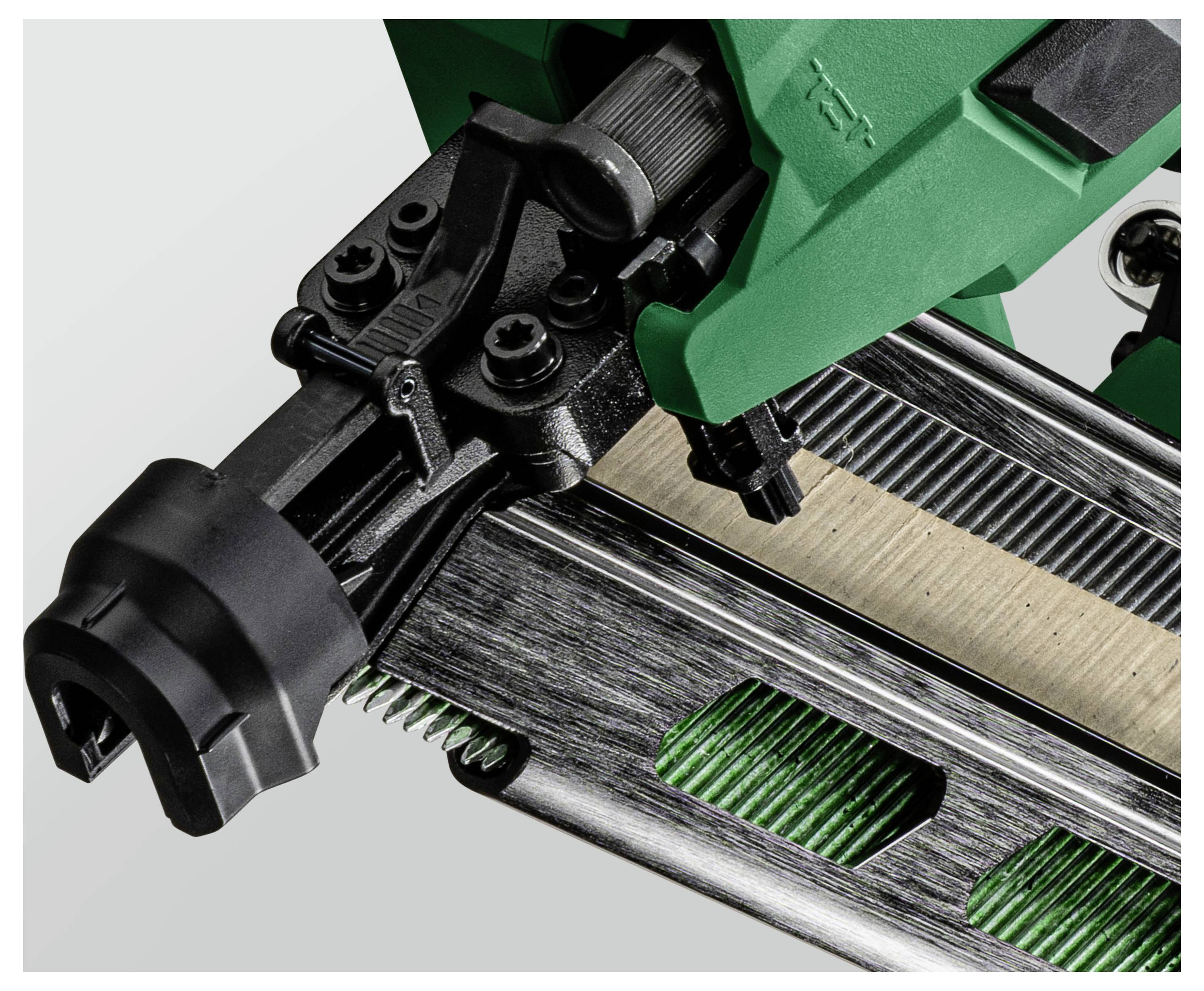 Un gros plan d'un outil agrafeur vert et noir, centré sur le mécanisme d'agrafage et les bandes d'agrafes métalliques, capturant sa construction détaillée.