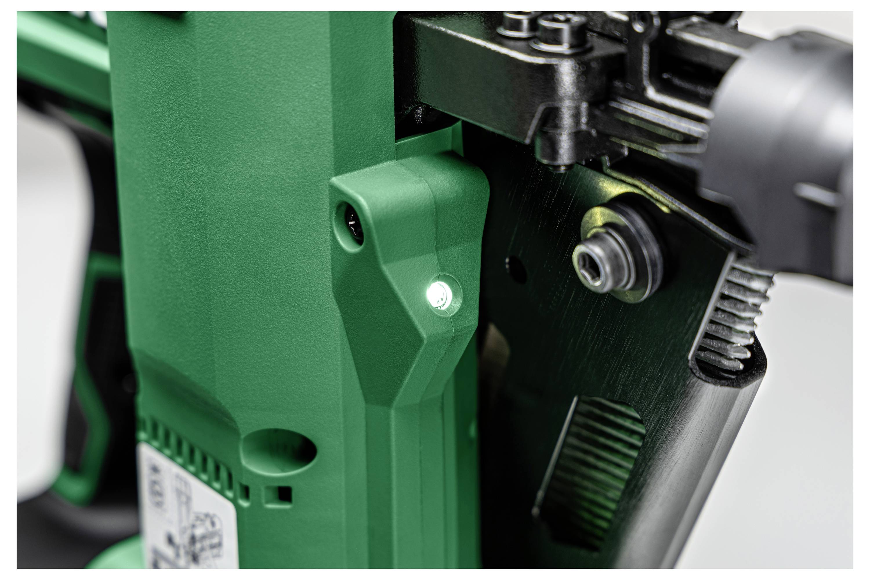 Gros plan d'un outil industriel vert et noir, avec une vis et un petit voyant LED.