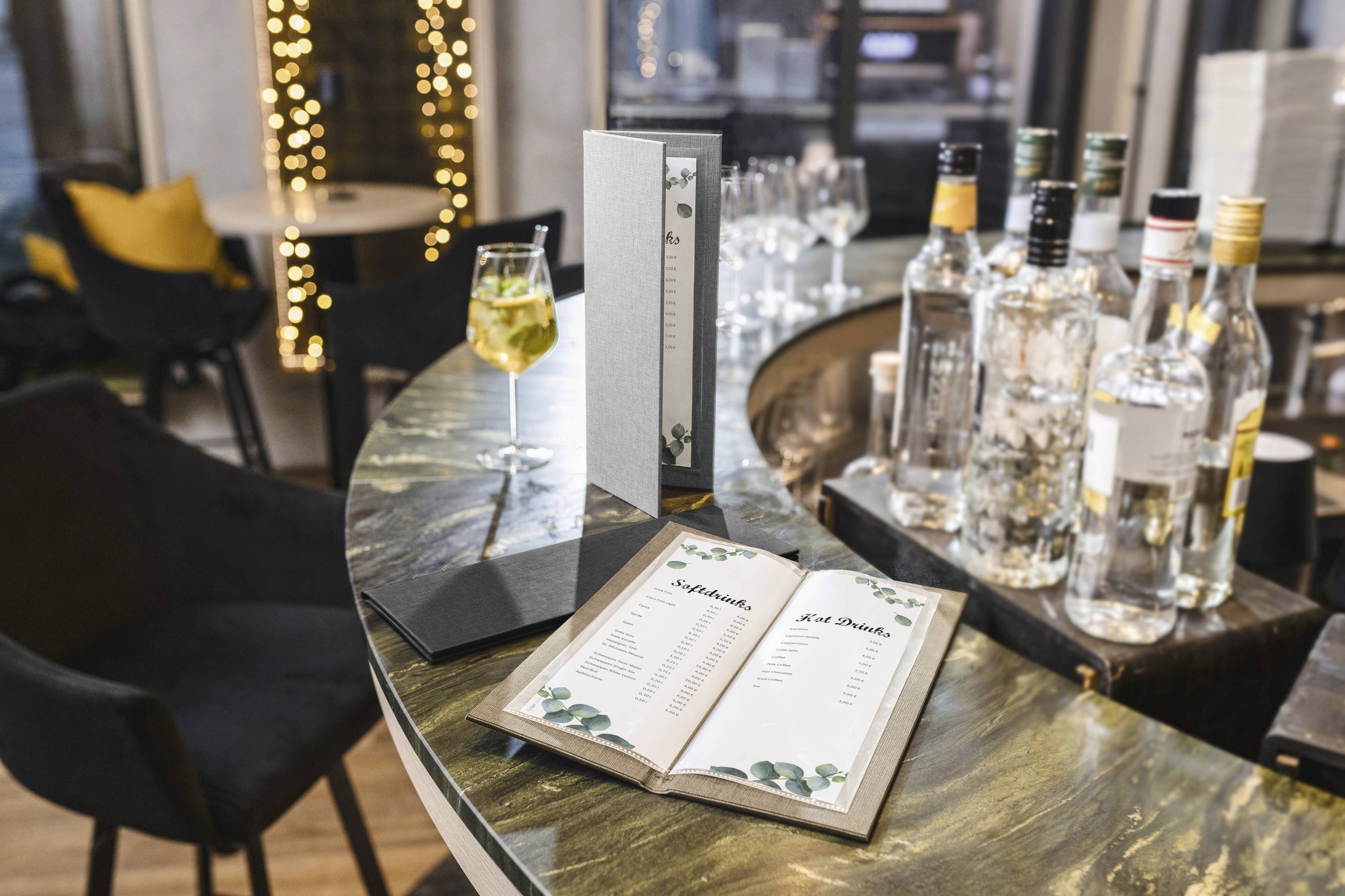 Un cadre de bar chic avec un menu de cocktails ouvert sur un comptoir en marbre, entouré de bouteilles d'alcool, d'un cocktail et de sièges élégants.