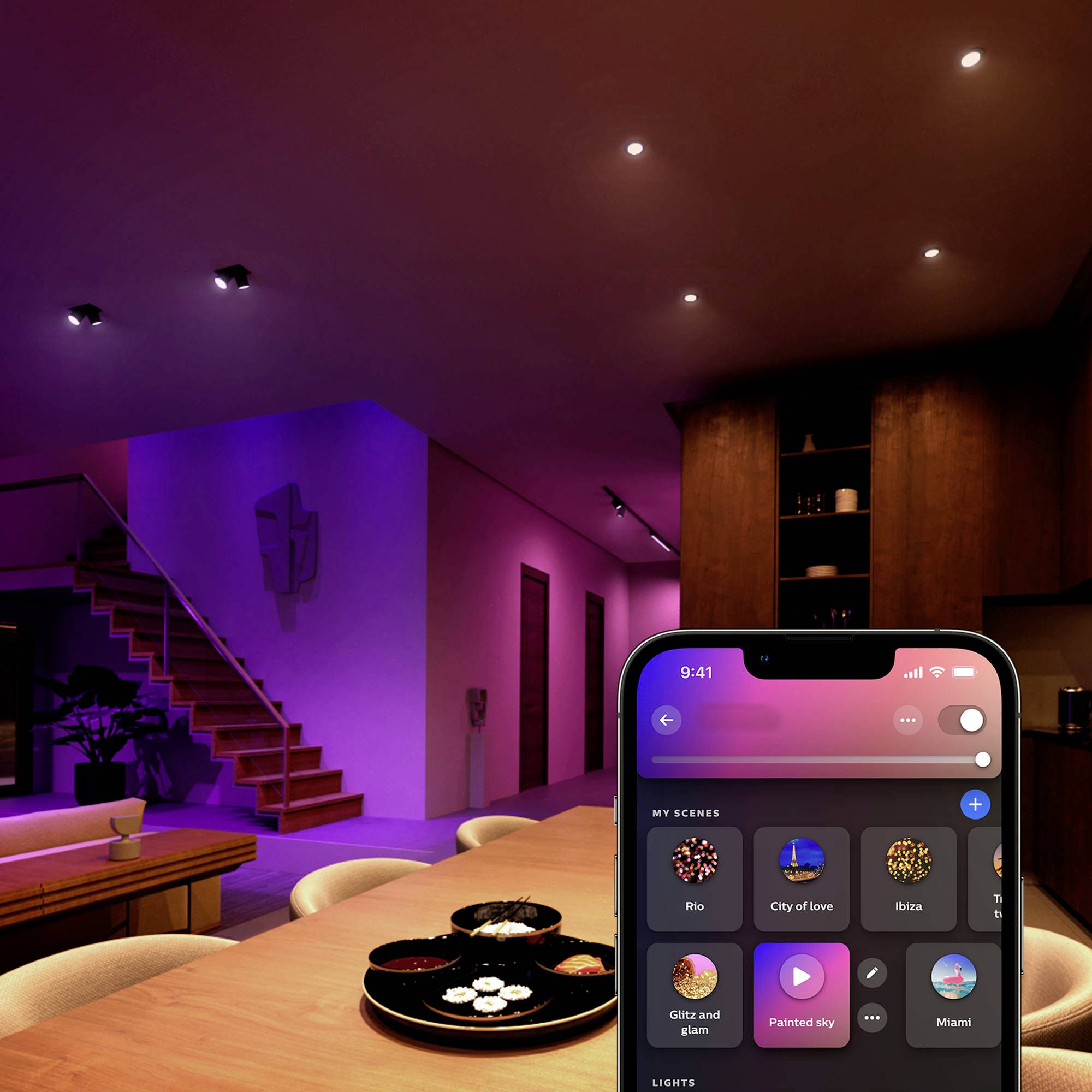 Un salon moderne avec un éclairage d'ambiance violet. Un smartphone affiche l'interface d'une application de gestion d'éclairage avec des scènes sélectionnables comme « Ville de l'amour ».