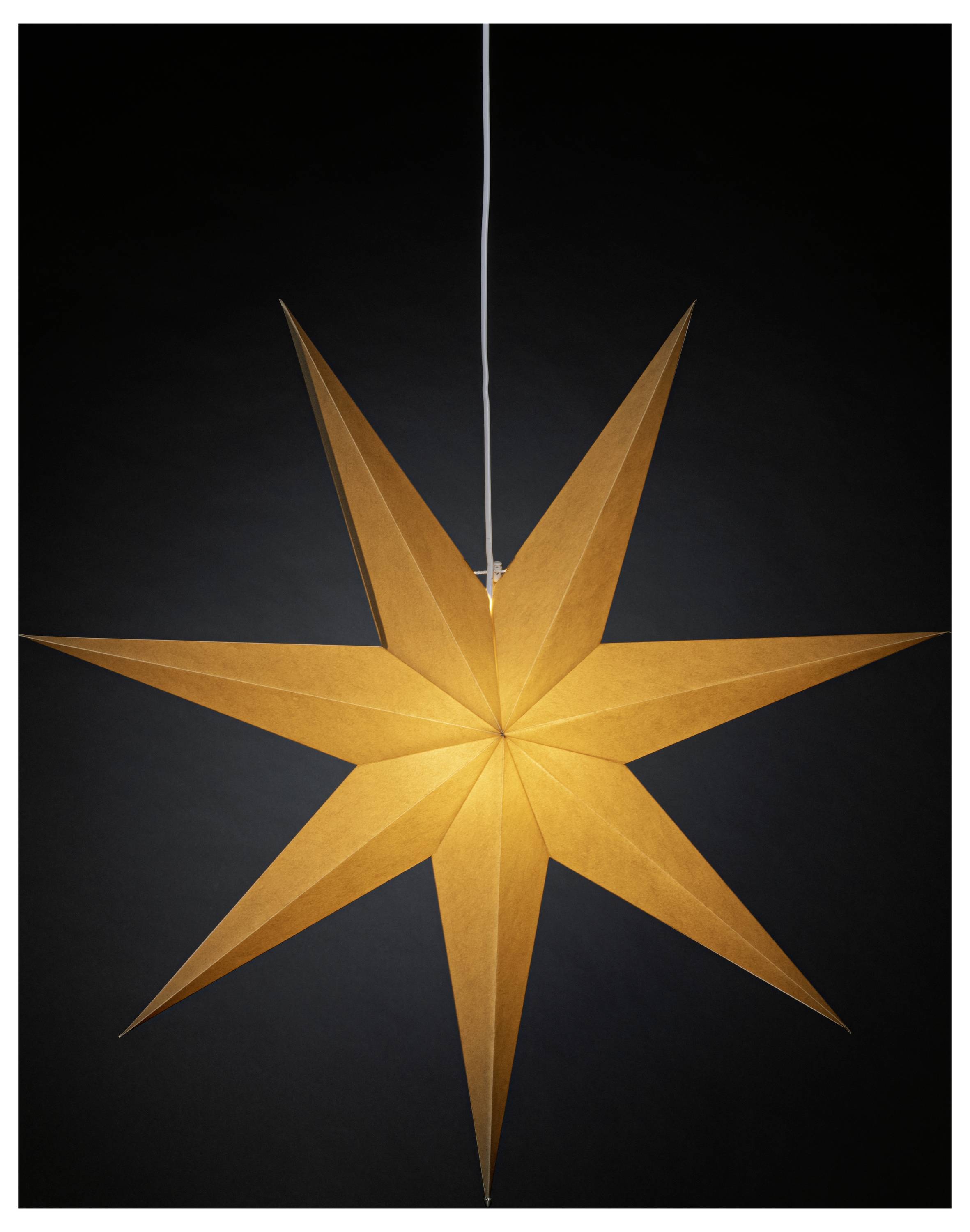 Un lampion en papier en forme d'étoile à huit branches, illuminé, est suspendu contre un fond sombre, créant un effet chaleureux et lumineux.