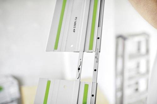 Gros plan sur une voie métallique segmentée avec des accents verts, probablement utilisée pour des outils ou la construction, montrant les détails de son mécanisme d'emboîtement.