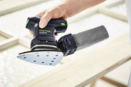 Une main tient une ponceuse Festool DTS 400 REQ, en train de lisser la surface d'un cadre en bois. La ponceuse est triangulaire avec un sac à poussière attaché.