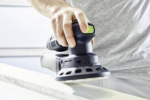 Une personne utilise une ponceuse orbitale électrique sur une surface en bois, la lissant par un mouvement circulaire dans un environnement d'atelier.