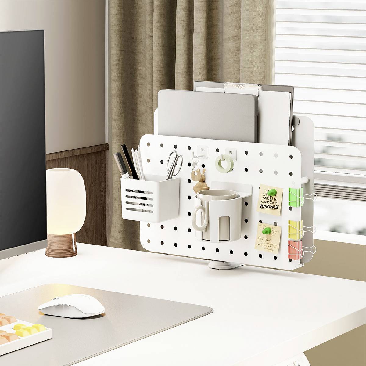 Un aménagement de bureau minimaliste avec un organisateur à panneau perforé tenant un porte-stylos, une tasse, des cahiers et des plantes décoratives près d'une fenêtre.