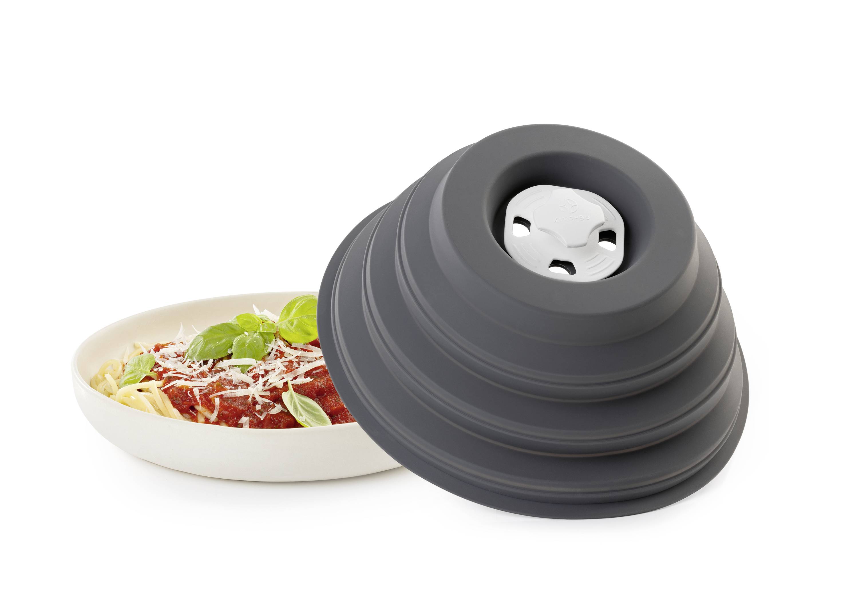 Une assiette de pâtes avec sauce tomate, garnie de basilic, à côté d'un couvre-plat en silicone gris pliable, partiellement ouvert.
