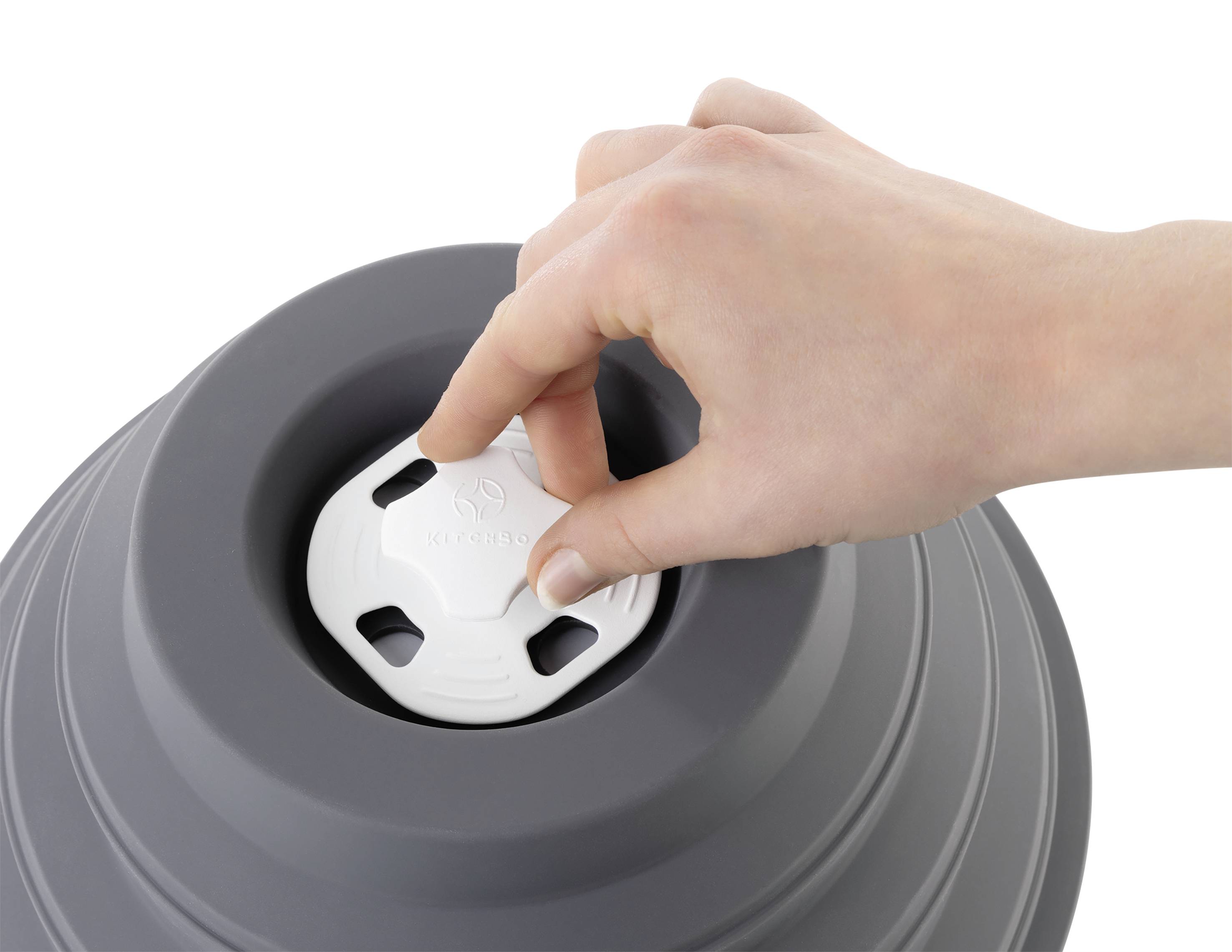 Une main verrouille le couvercle d'un récipient gris en silicone pliable, mettant en valeur sa fonction de rangement.