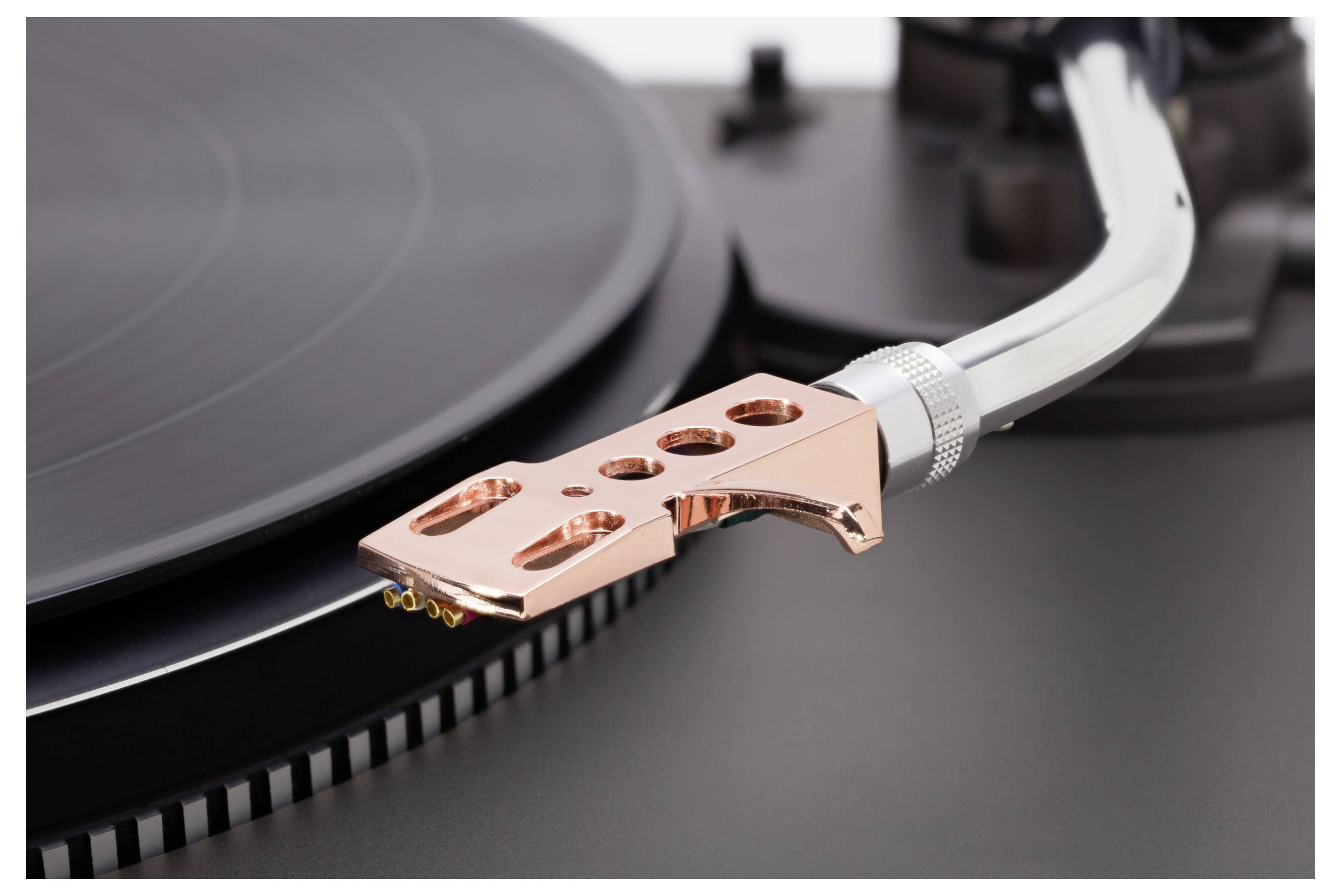 Un gros plan du bras de lecture et du stylet d'une platine vinyle positionnés sur un disque vinyle, mettant en valeur la précision de l'aiguille et des sillons.