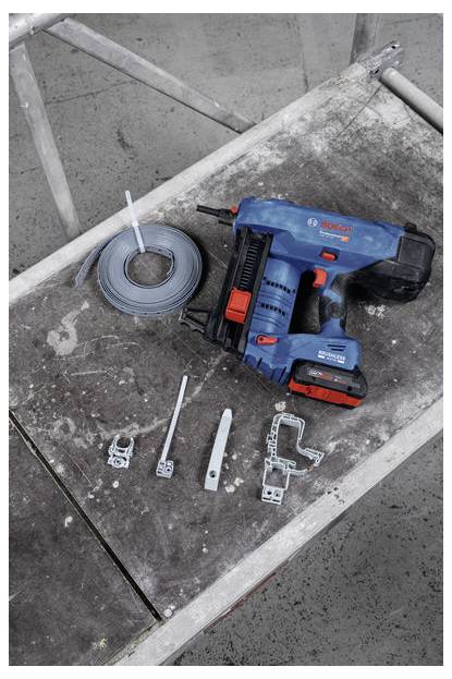 Un outil électrique sans fil et divers composants métalliques sont disposés sur un établi usé, suggérant un projet de construction ou de bricolage.