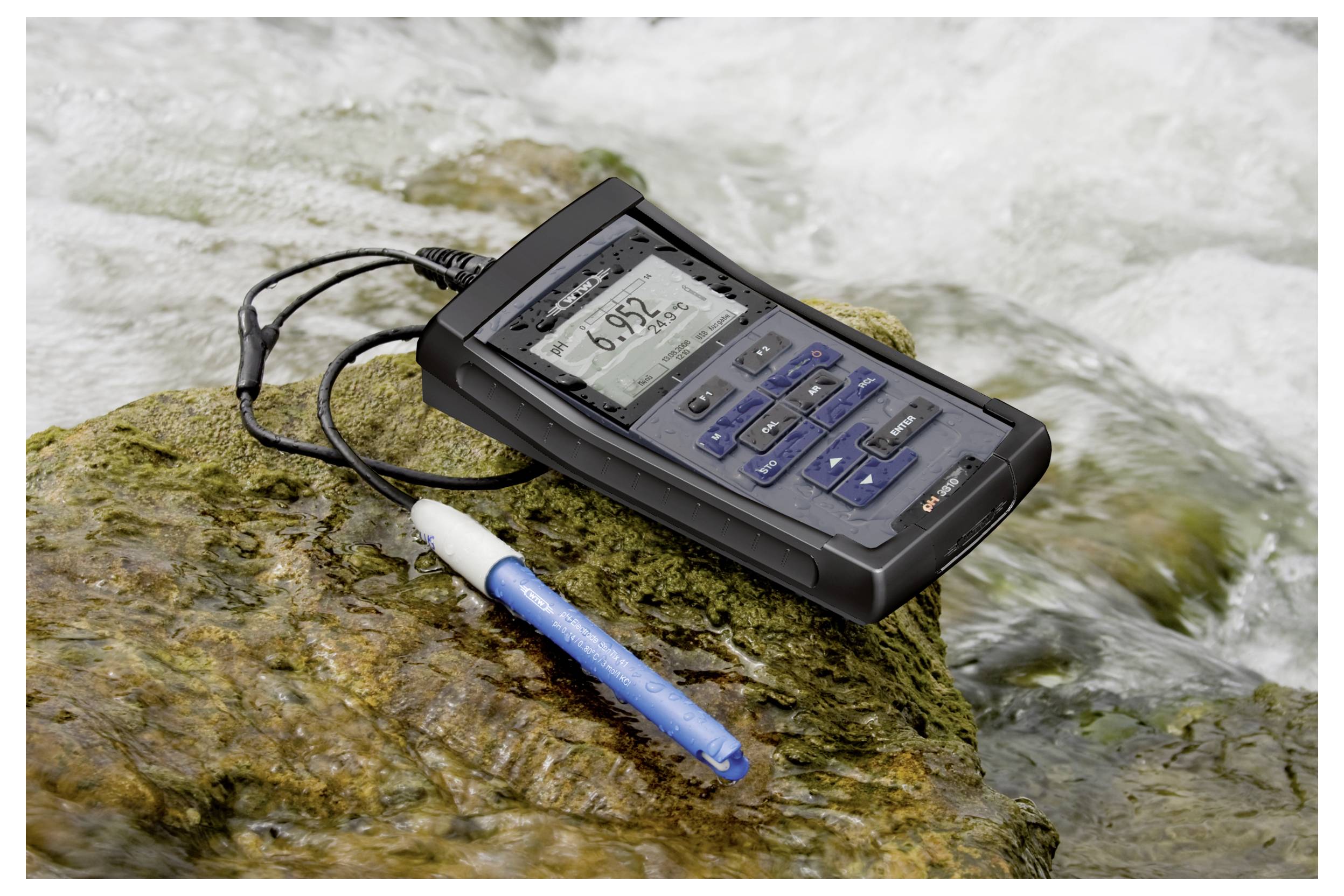Un testeur numérique portable de qualité de l'eau affiche une lecture de 6,92 sur une surface rocheuse près d'un cours d'eau, à côté d'une sonde capteur bleue.