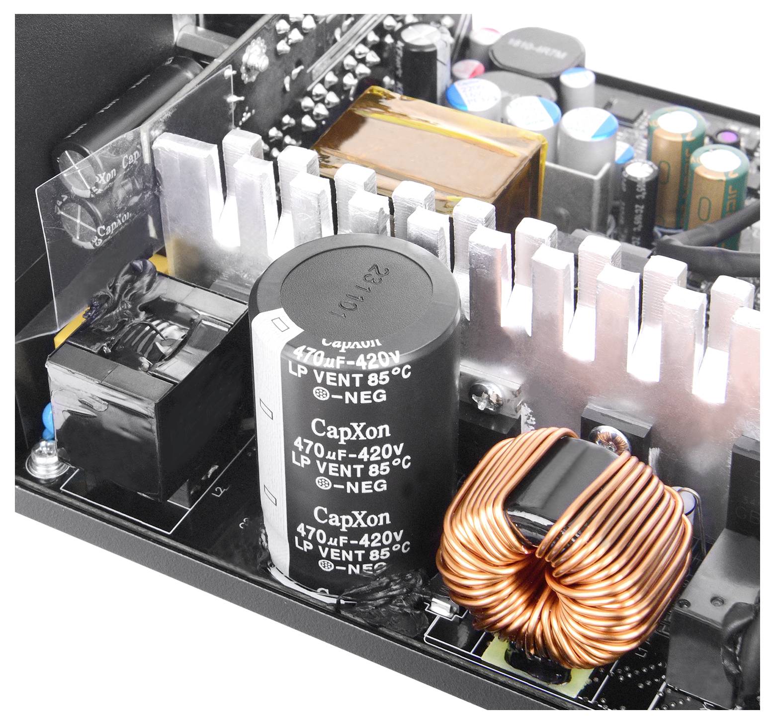 Vue intérieure d'un bloc d'alimentation électrique montrant des condensateurs, des dissipateurs thermiques et une bobine de cuivre, mettant en valeur les composants électroniques de l'appareil.