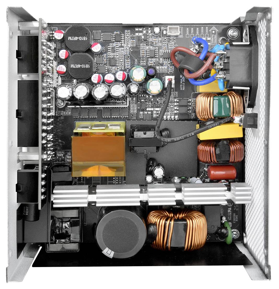 Une vue de dessus de l'intérieur d'un bloc d'alimentation d'ordinateur, montrant des condensateurs, des bobines et divers composants électroniques sur une carte de circuit imprimé.