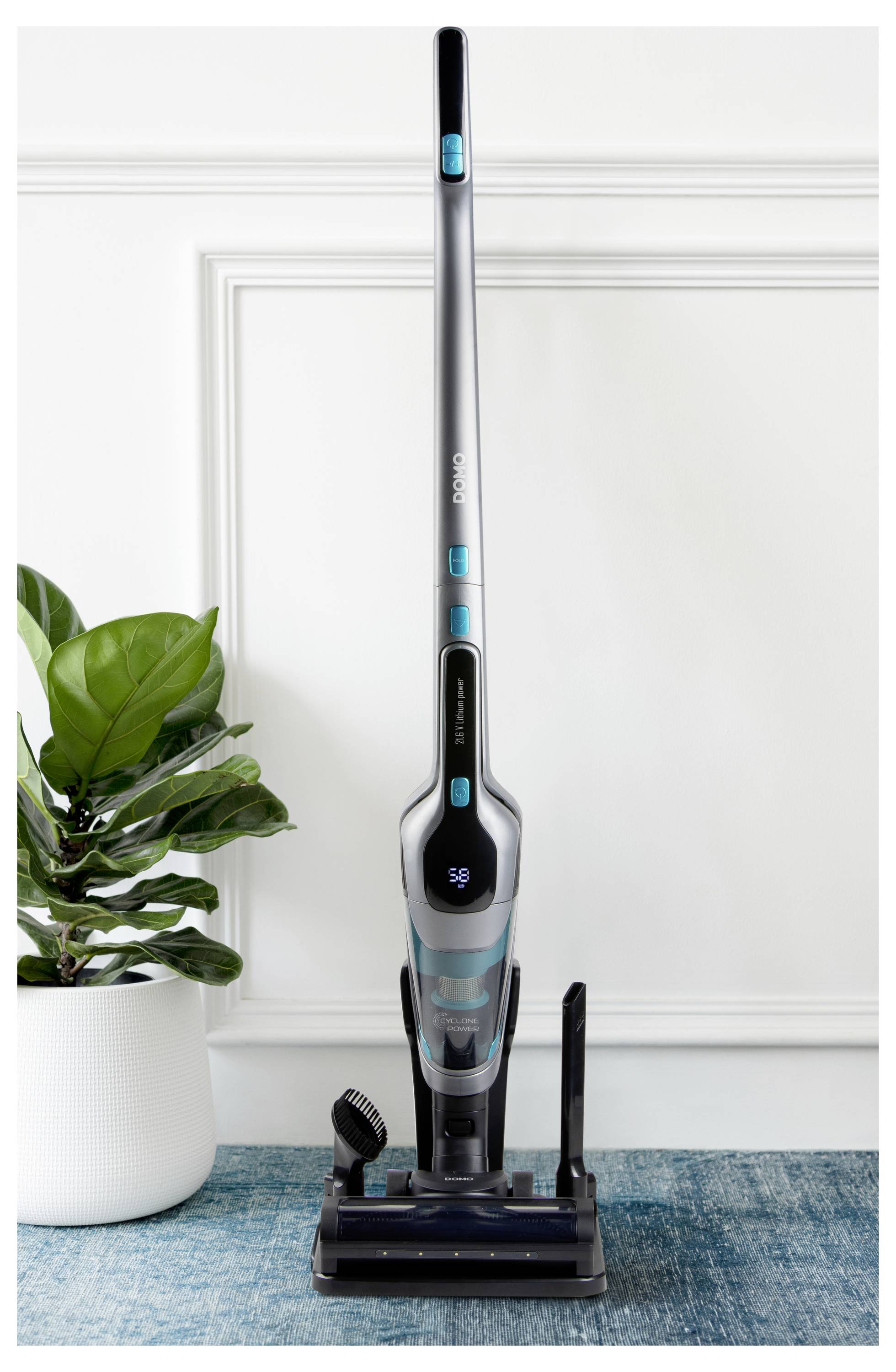 Un aspirateur sans fil élégant et vertical dans une pièce moderne avec une plante verte.