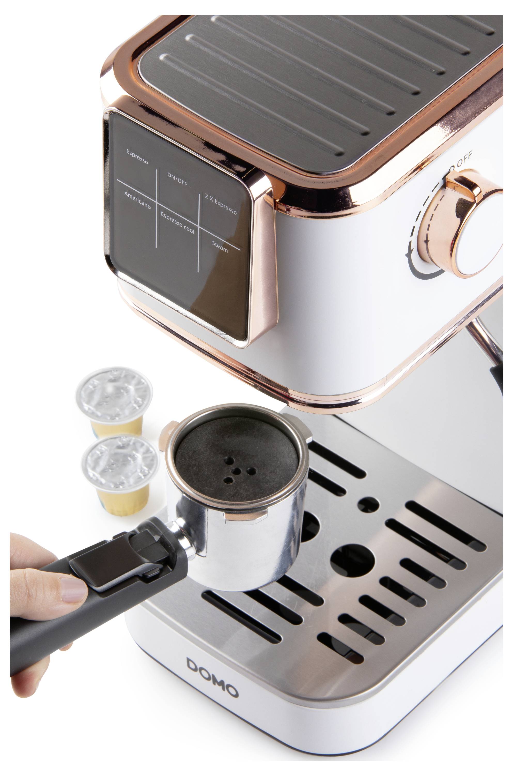 Une personne place un portafiltre rempli de café moulu dans une machine à espresso élégante et moderne. Deux capsules sont posées à proximité.