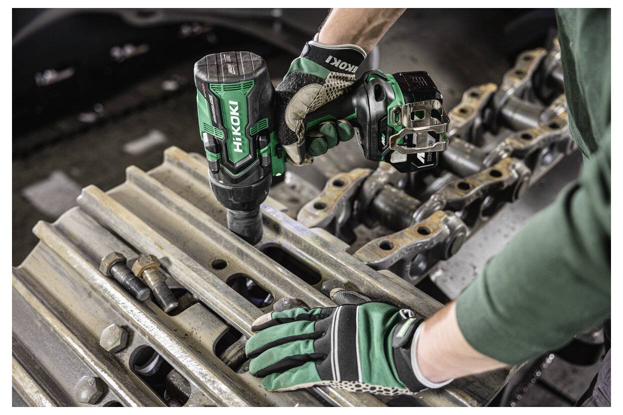 Une personne portant des gants utilise un outil électrique HiKOKI pour serrer un boulon sur une structure métallique.