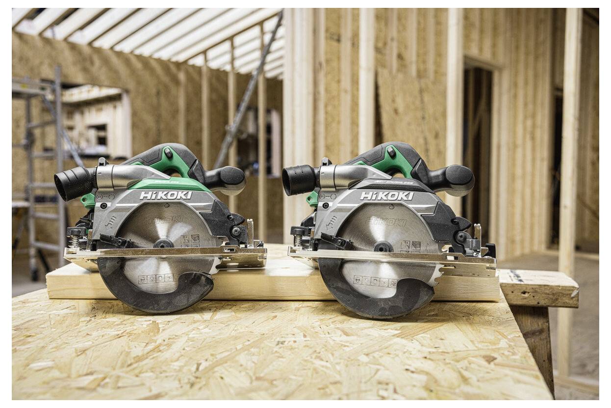 Scies circulaires 'HiKOKI' posées sur une surface en bois, dans un environnement de construction avec des charpentes et des poutres en bois en arrière-plan.