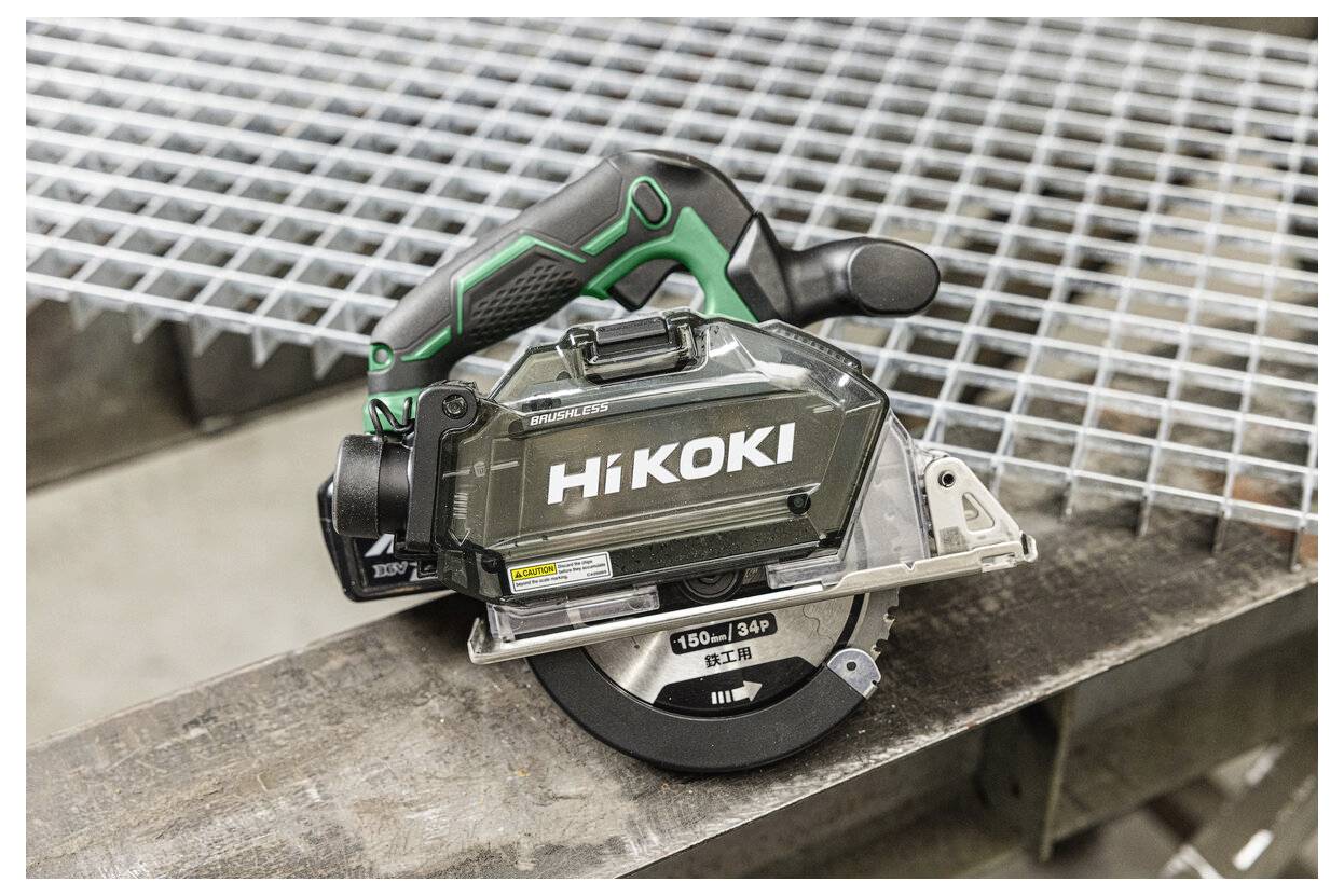 Une scie circulaire sans fil avec une poignée noire et verte, de la marque « HiKOKI », repose sur une grille métallique, mettant en valeur sa portabilité et son design.