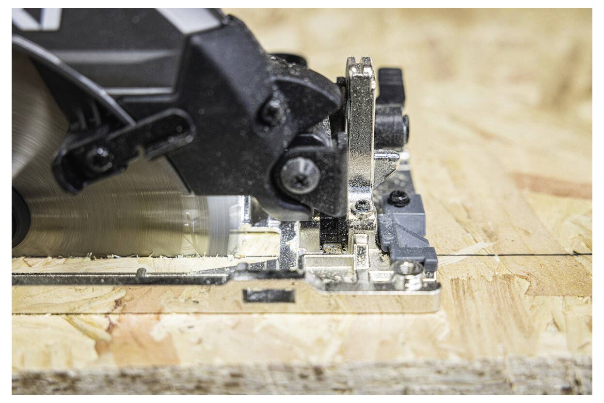 Une scie circulaire coupe à travers un morceau de bois, mettant en valeur un artisanat précis et la texture de la surface en bois.