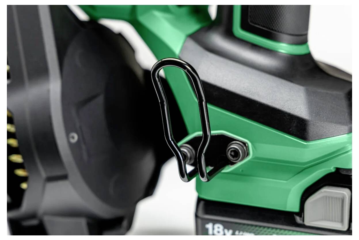 Gros plan sur un outil électrique vert et noir avec un crochet métallique fixé sur la poignée pour le suspendre, une partie de sa batterie 18V est visible.