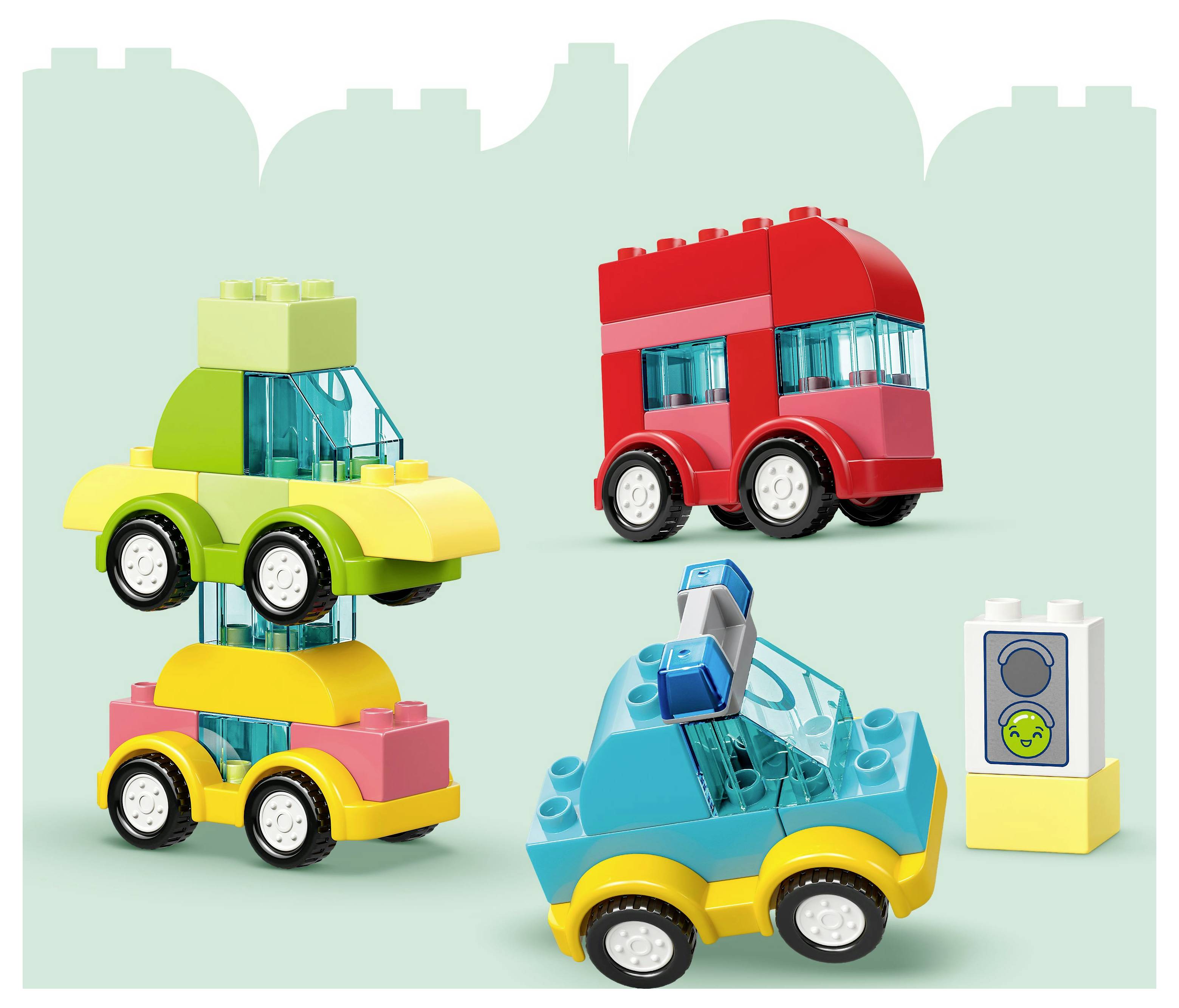 Des blocs de construction forment des véhicules colorés ; un camion vert et jaune, un bus rouge et une voiture bleue. Un bloc avec un visage souriant se trouve à proximité.
