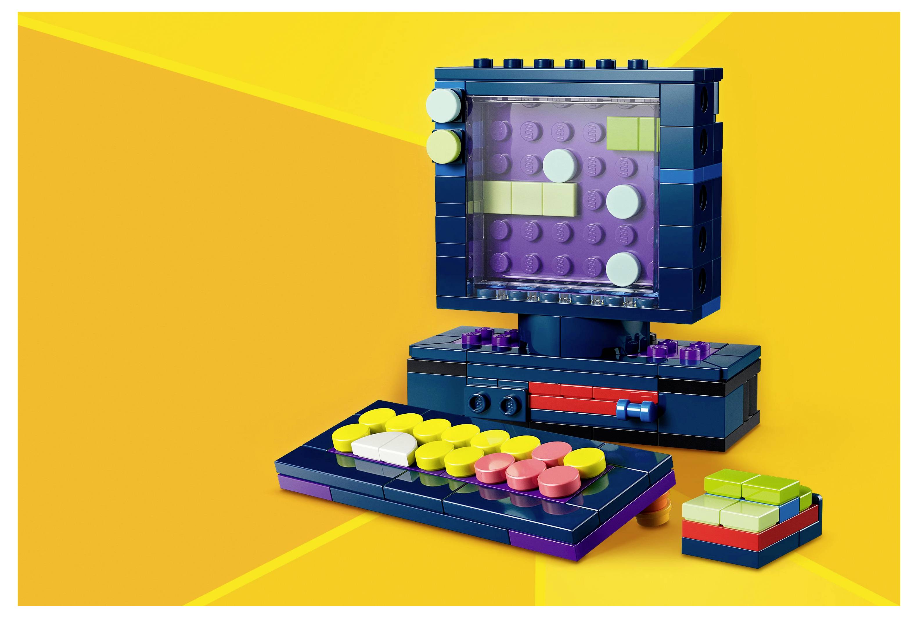 Un ensemble de jouets bloc colorés ressemblant à un ordinateur rétro avec un clavier sur un fond jaune vif.