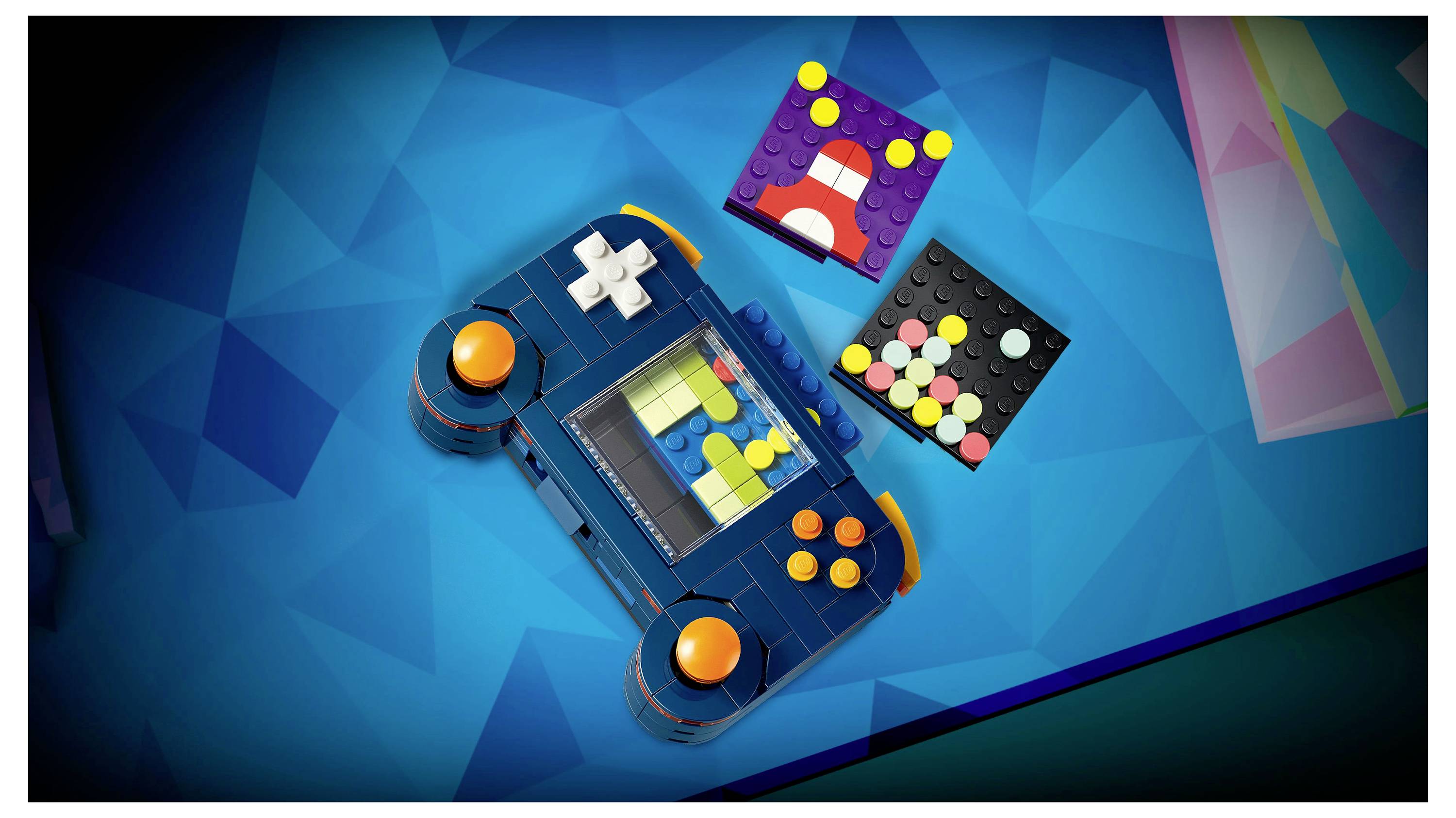 Une manette de jeu colorée et deux blocs de construction de type LEGO avec des motifs abstraits, sur un fond géométrique bleu.
