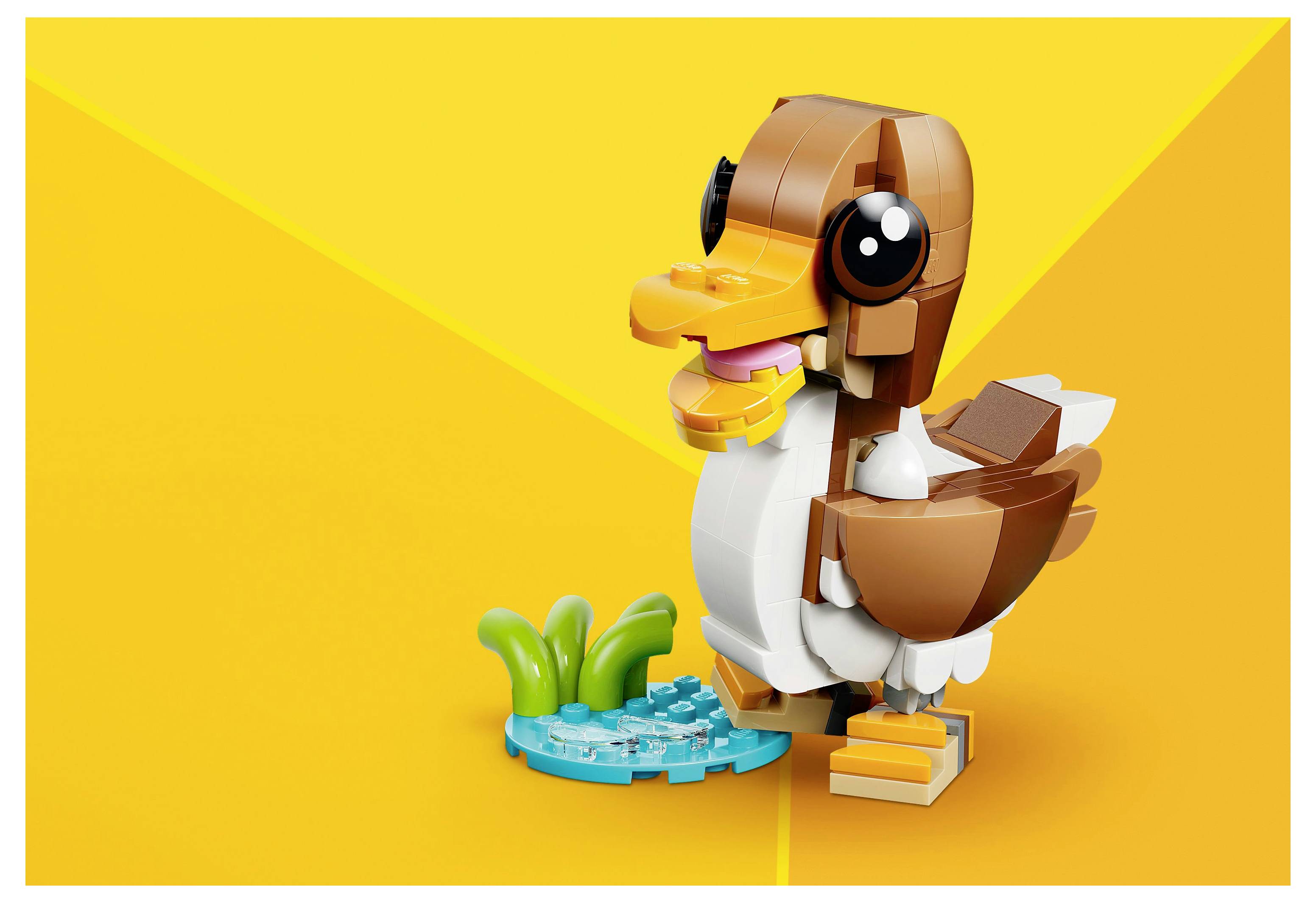 Un canard LEGO au visage souriant se tient à côté d'un petit étang avec des plantes vertes sur un fond jaune vif.