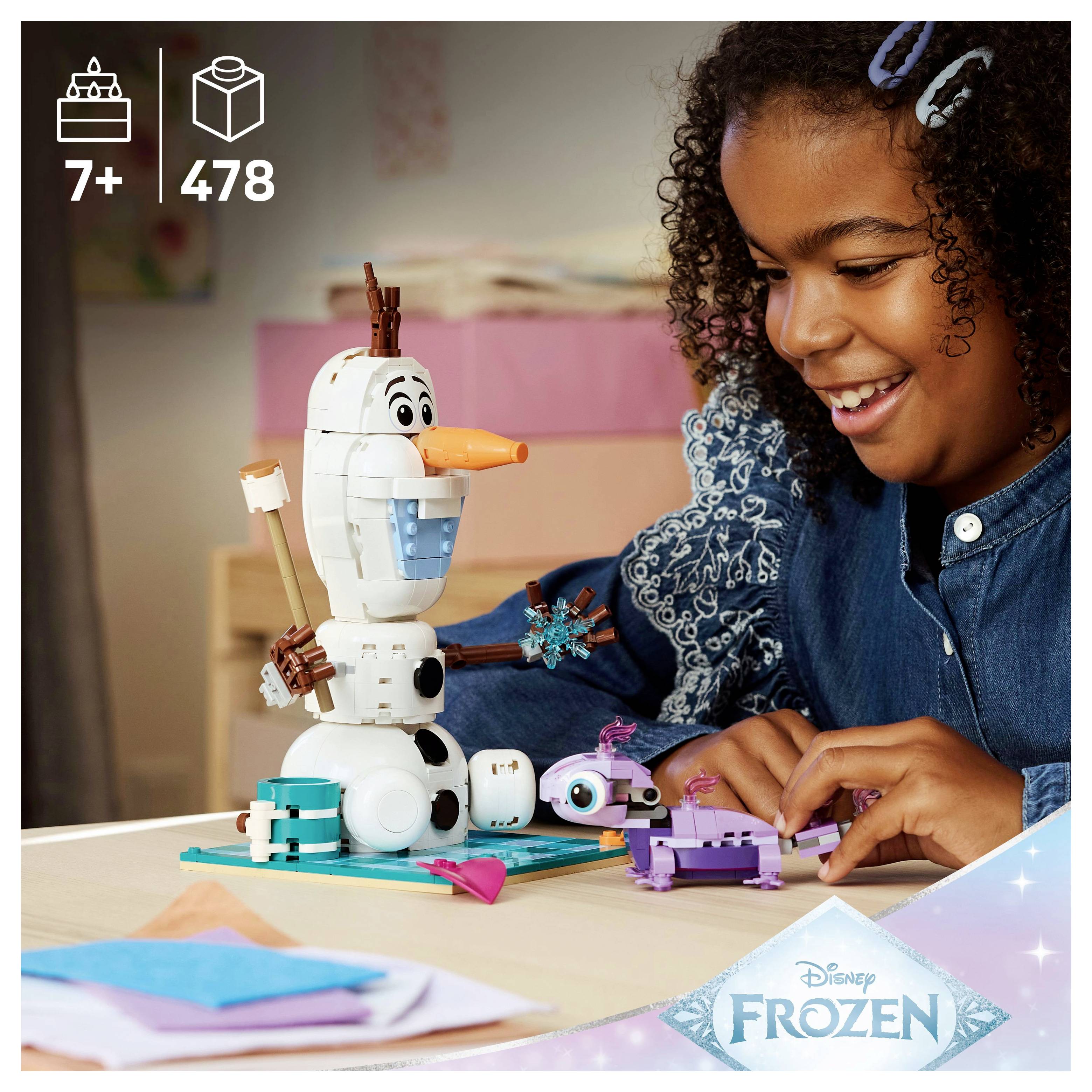 Un enfant assemble un ensemble de jouets sur le thème de 'La Reine des Neiges', avec Olaf, sur une table. La boîte indique qu'il est recommandé pour les enfants de 7 ans et plus, avec 478 pièces.