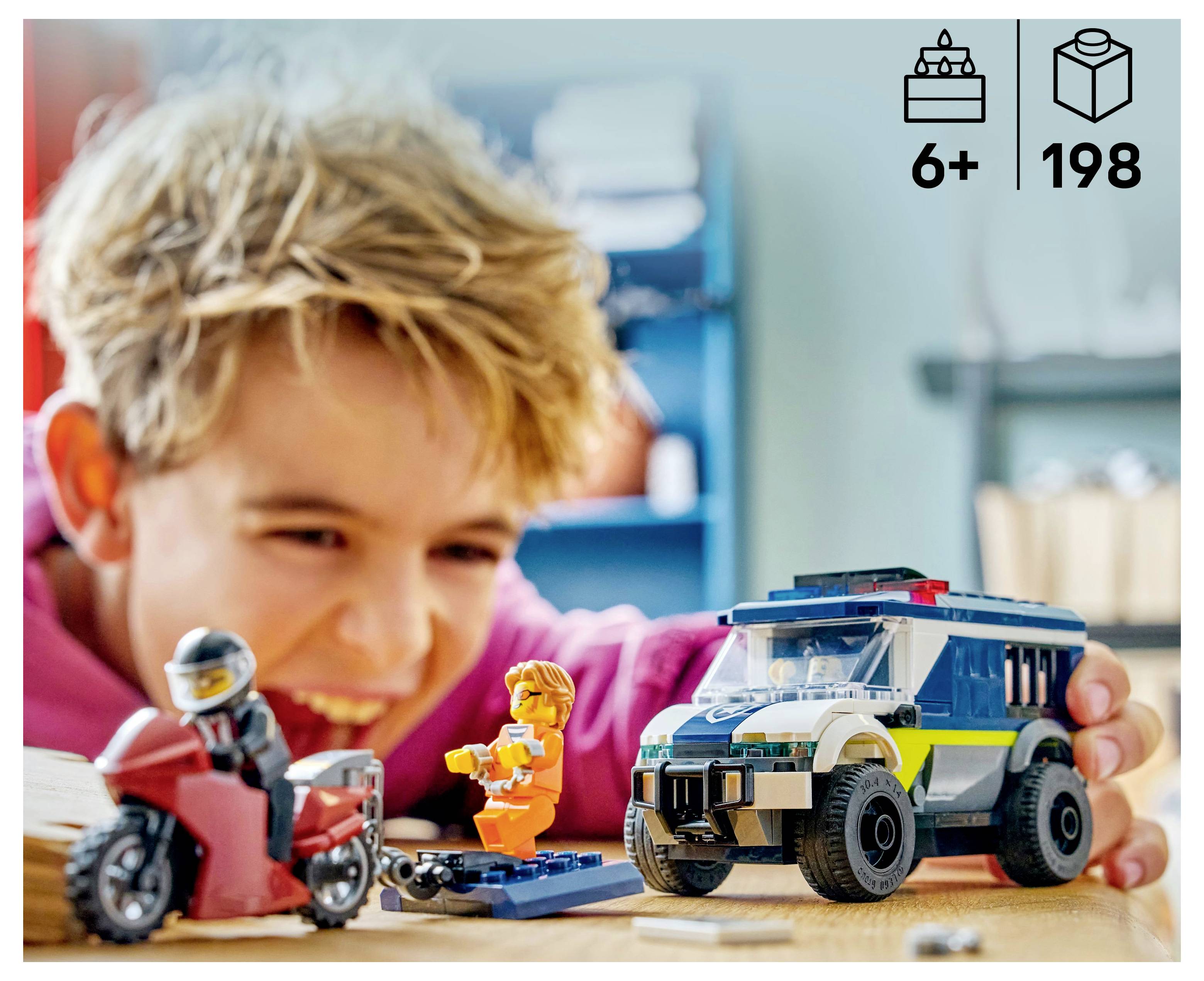 Un enfant joue avec enthousiasme à une moto jouet et une voiture de police jouet sur une table. L'emballage indique '6+' comme âge et '198' pièces.