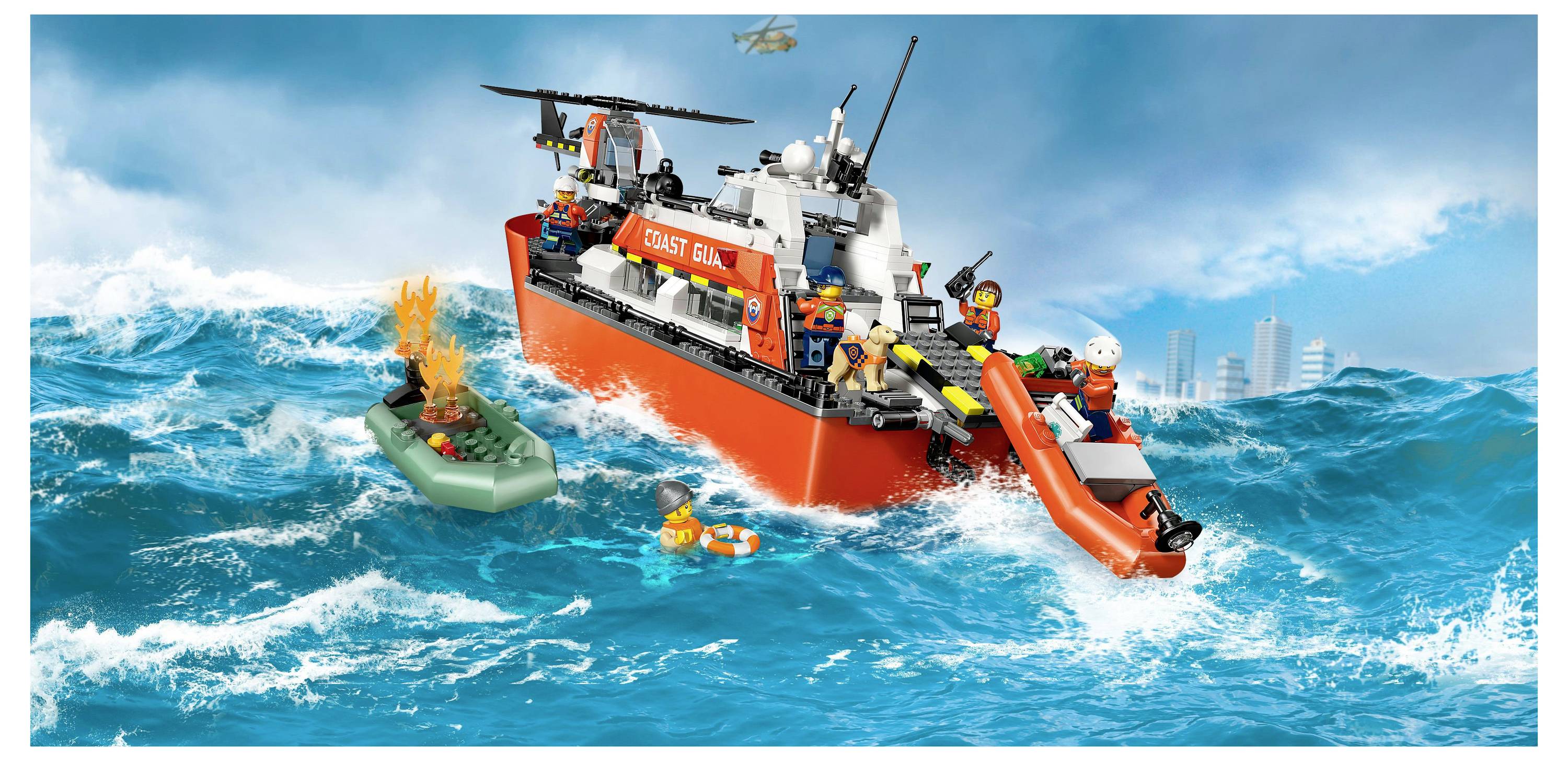 Un navire de la Garde côtière jouet dans des mers agitées avec un hélicoptère au-dessus. Des membres d'équipage sauvent une personne d'un canot de sauvetage en utilisant un radeau pneumatique.