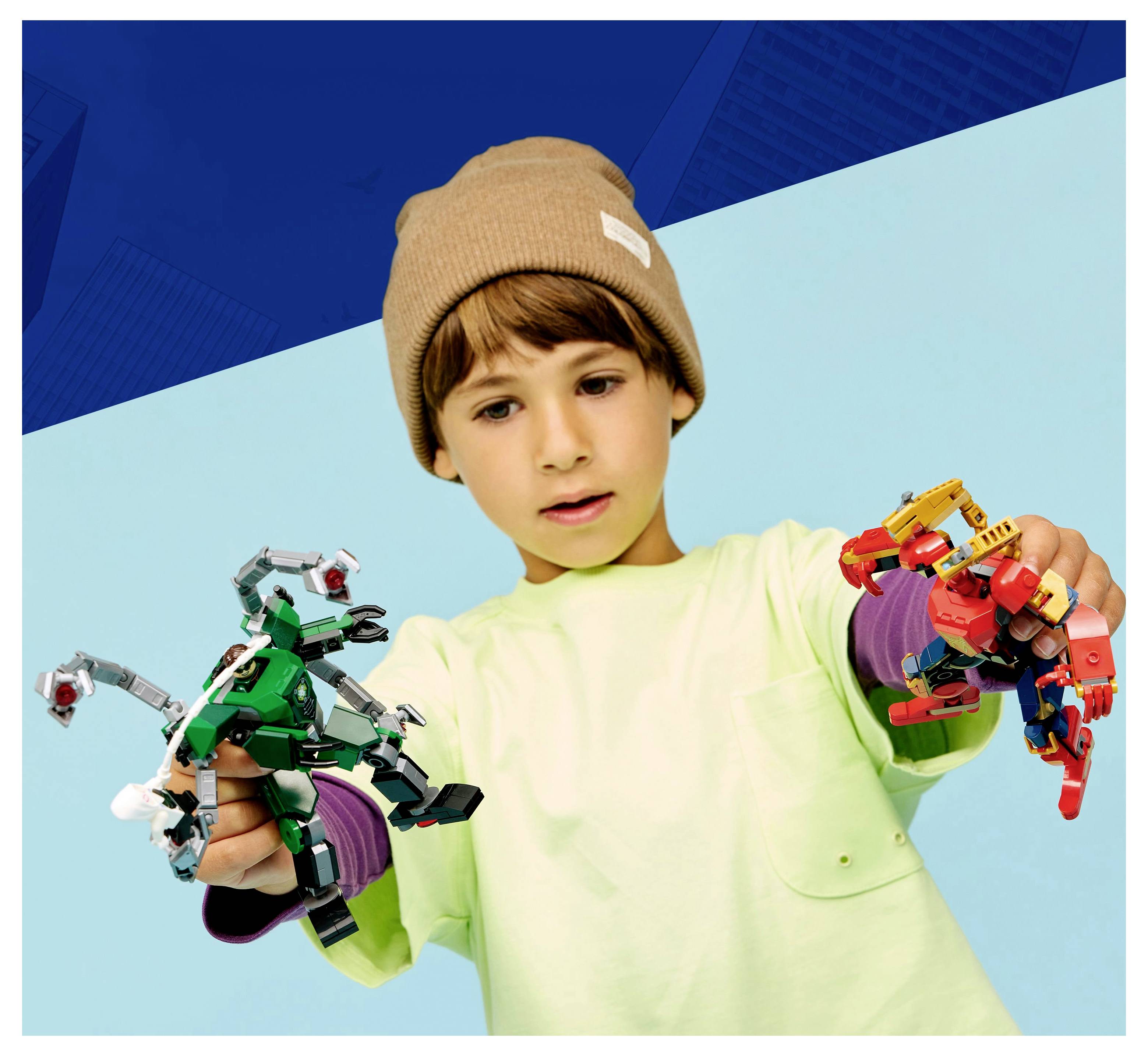 Un enfant portant un bonnet beige joue avec des jouets robotiques colorés, tenant un robot dans chaque main contre un fond bleu.