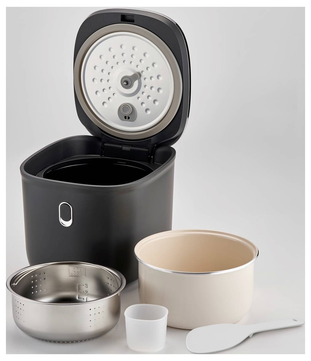 Un cuiseur à riz électrique ouvert avec une cuve amovible, un panier de cuisson à la vapeur, une tasse à mesurer et une cuillère à riz, tous disposés.