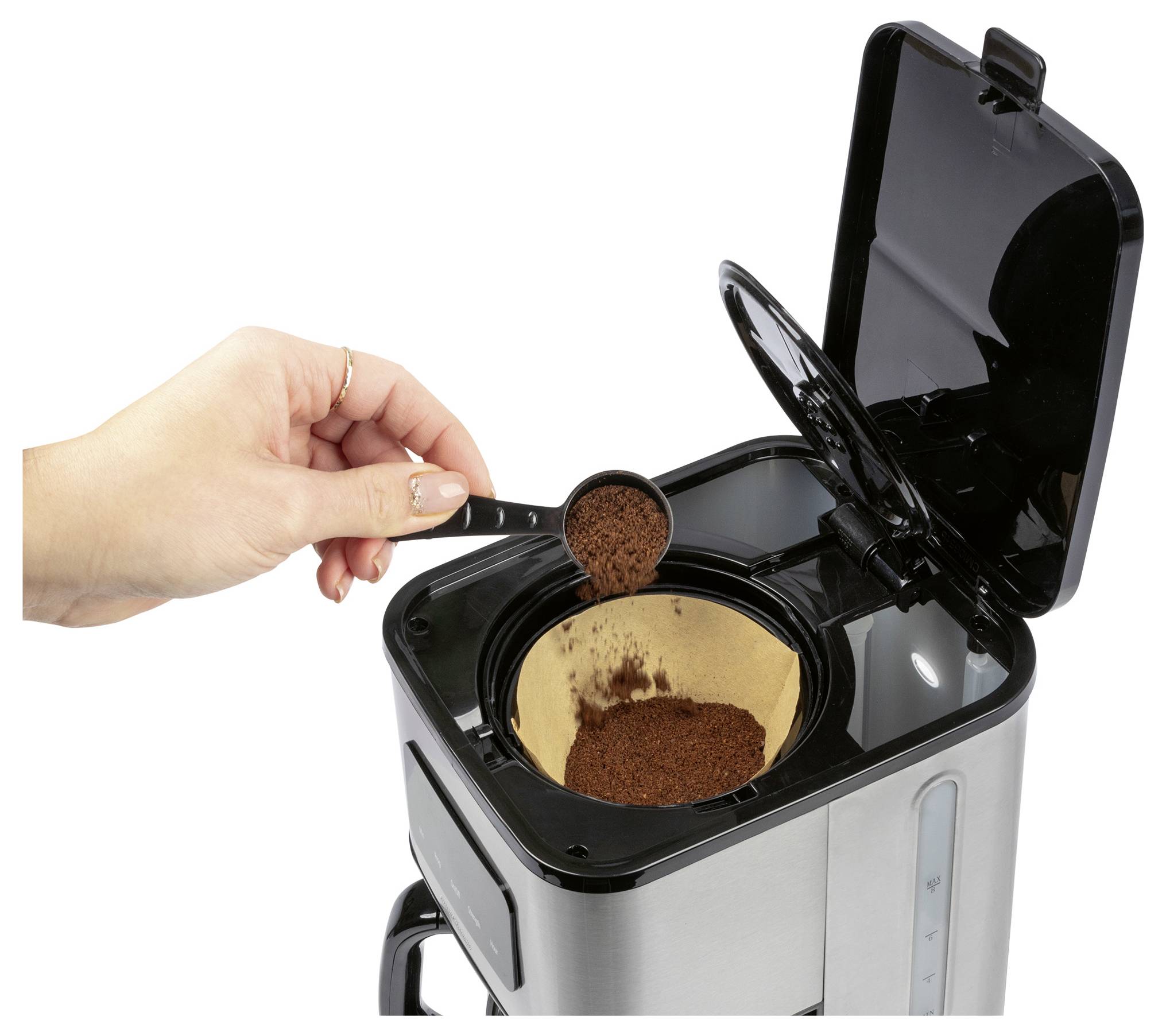 Une main ajoutant du café moulu dans un cafetière avec un couvercle ouvert, montrant un filtre à l'intérieur.