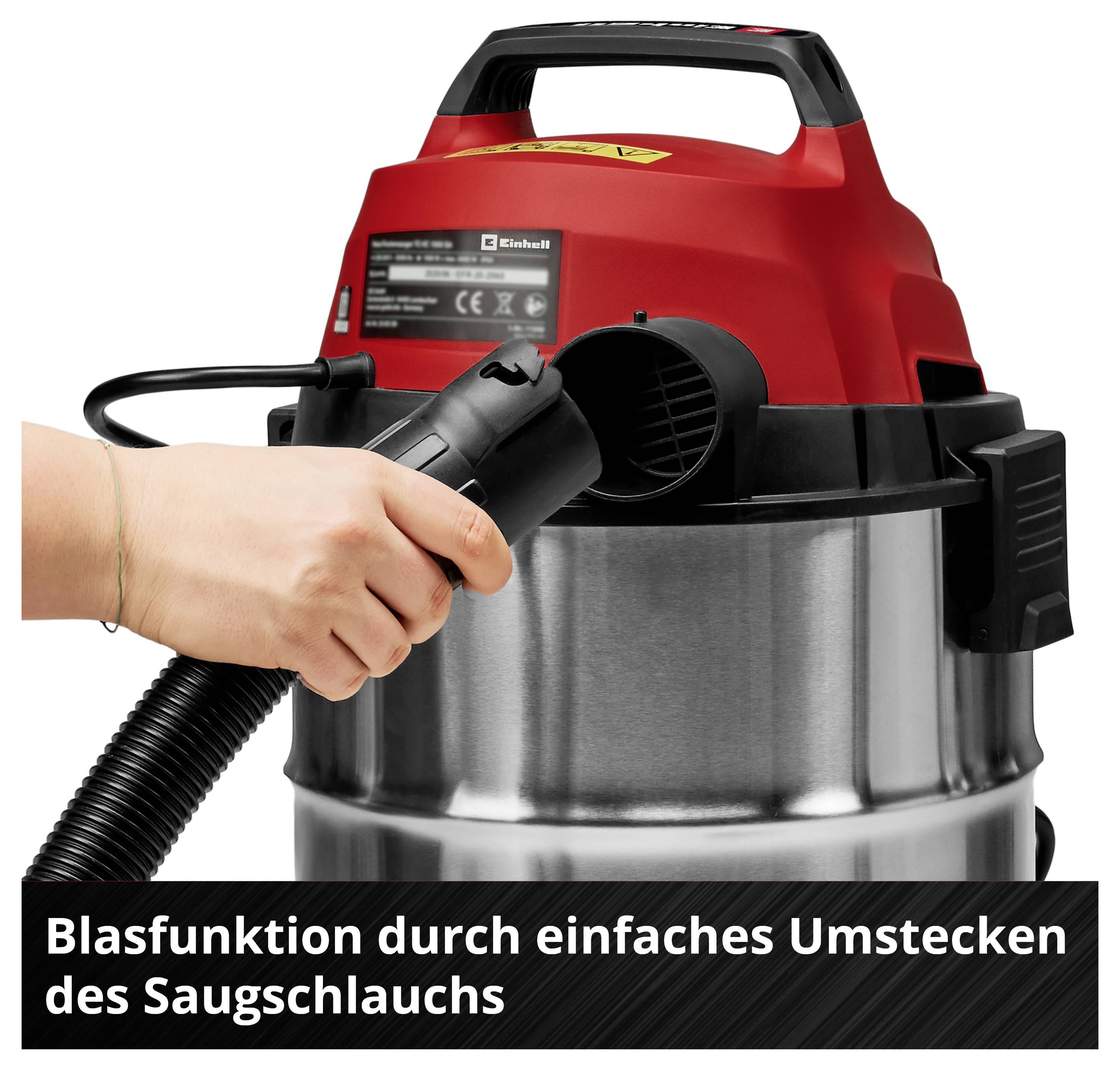 Un aspirateur avec un couvercle rouge et un tuyau noir. Une main manipule le tuyau pour activer la fonction soufflerie.