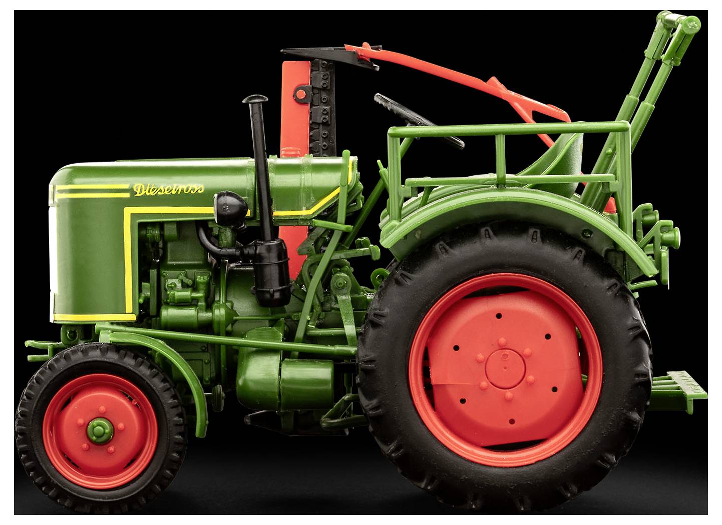 Un tracteur vintage vert et rouge sur un fond noir, montrant son profil latéral. Il possède des roues rouges distinctives et des pièces de moteur détaillées.