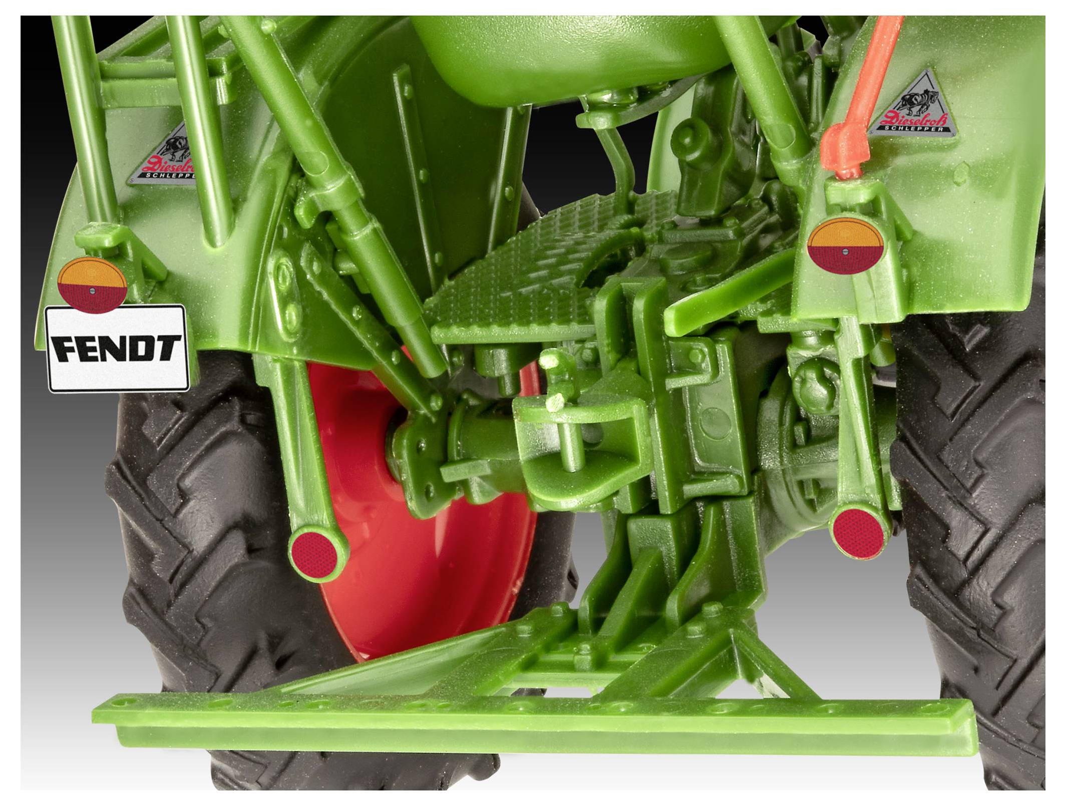 Vue rapprochée de l'arrière d'un tracteur Fendt vert avec des roues rouges, montrant des détails mécaniques et une plaque d'immatriculation.