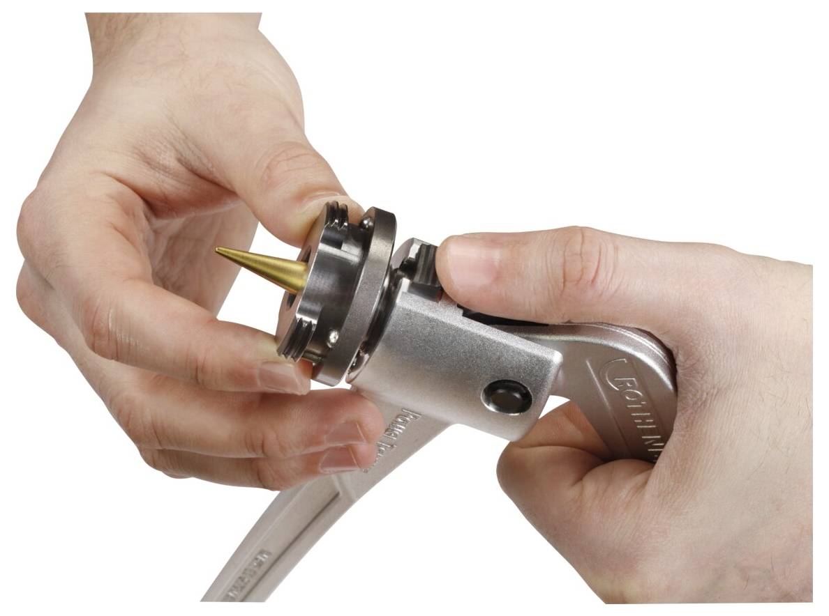 Mains utilisant un outil de perforation avec une pointe métallique et une clé à molette pour percer des trous, soulignant la fonction de ces outils dans l'artisanat ou la réparation.