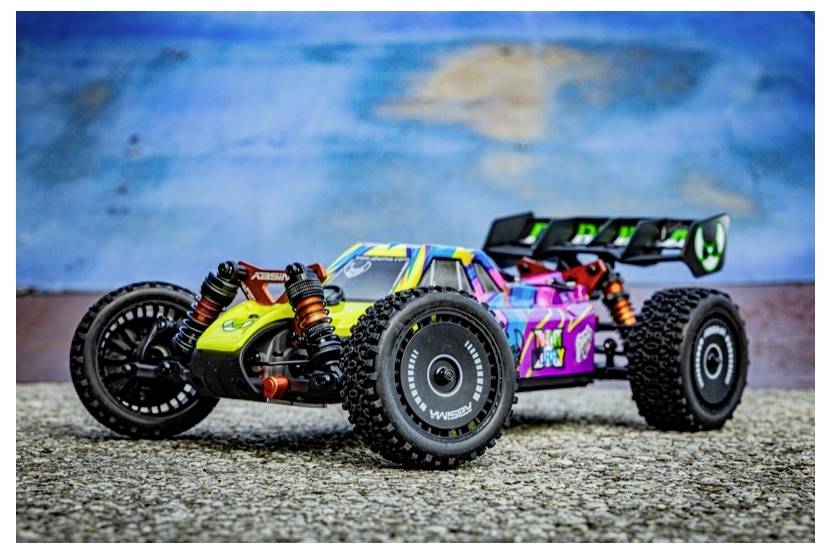 Une voiture télécommandée colorée avec de grandes roues tout-terrain sur une surface texturée, sur un fond flou bleu et marron.
