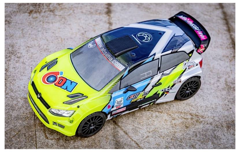 Une voiture de rallye miniature avec un design vibrant vert, blanc et noir, arborant divers logos de sponsors et des motifs complexes sur une surface en pierre.