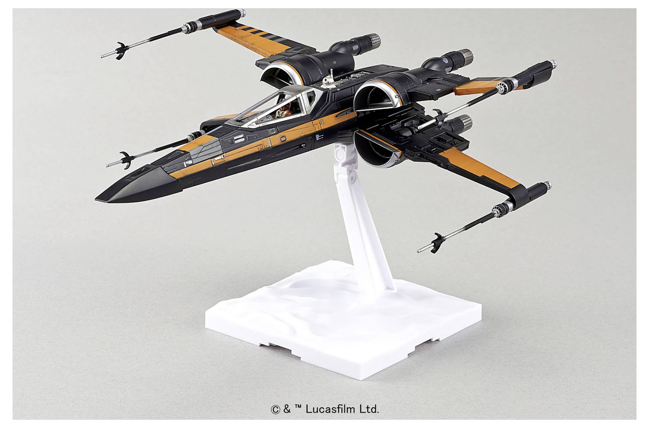 Un modèle d'un vaisseau spatial noir et orange ressemblant à un « X-wing » d'une série de science-fiction populaire, présenté sur un socle blanc.