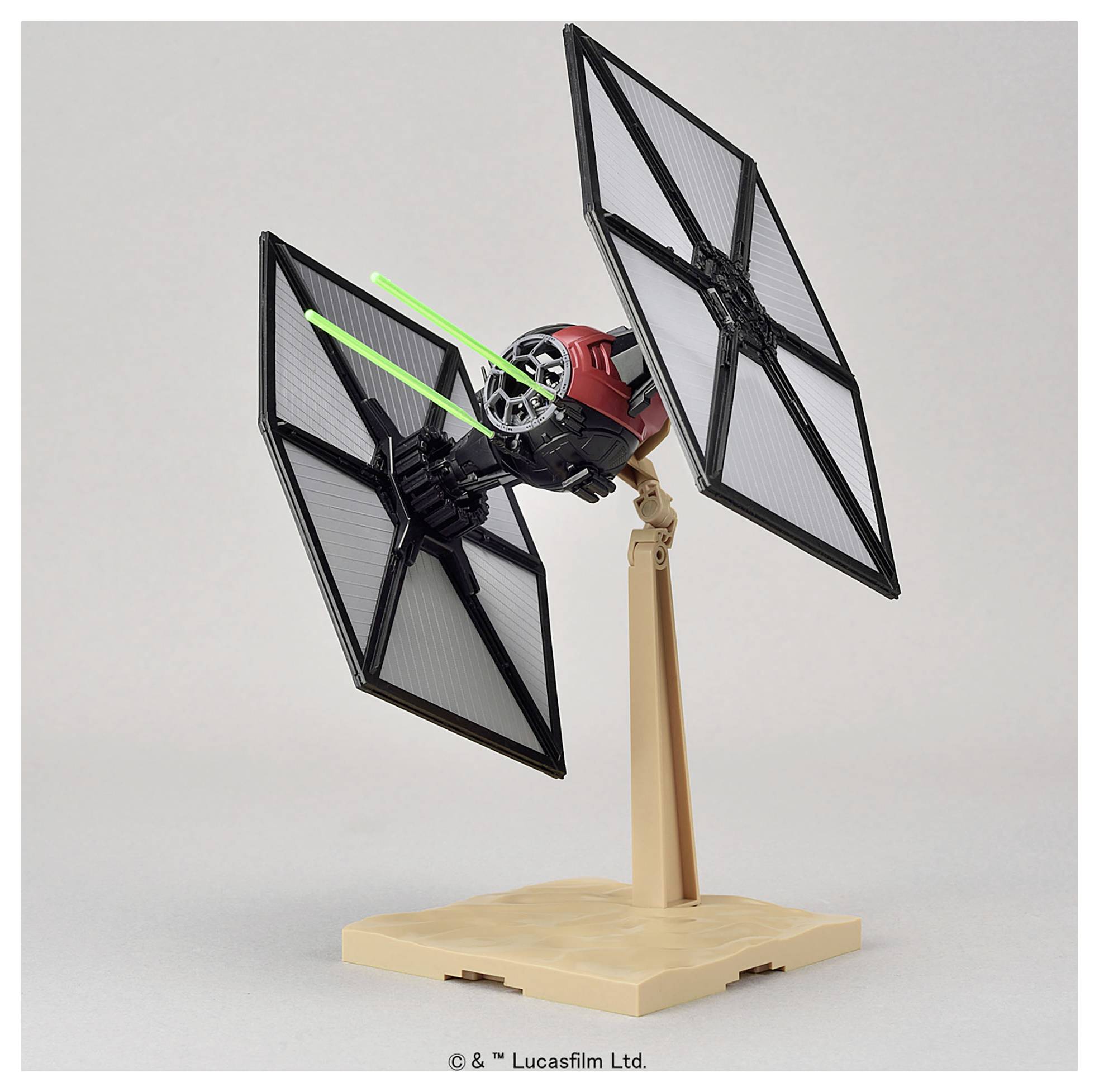 Un modèle d'un vaisseau TIE fighter de Star Wars, monté sur un socle. Deux faisceaux laser verts sont représentés sortant de l'avant.