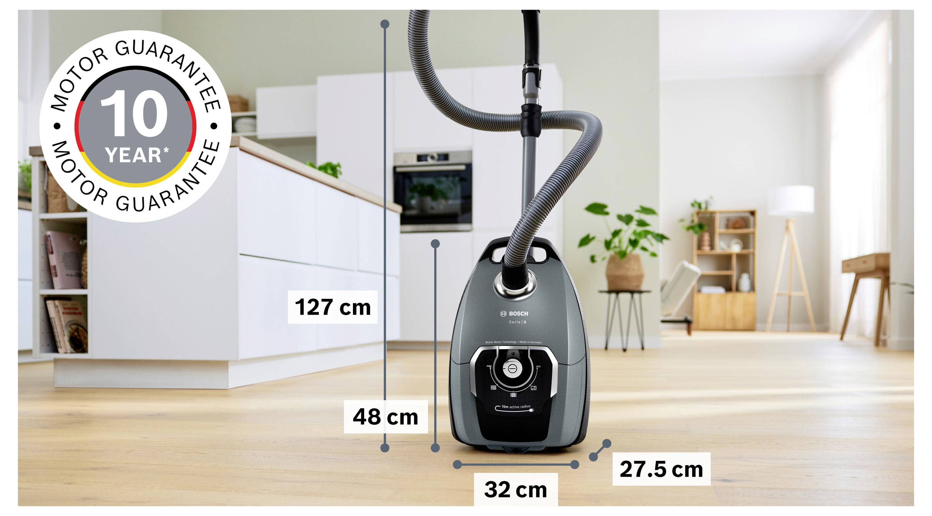 Un aspirateur avec tuyau posé sur le sol d'une cuisine. Dimensions indiquées : hauteur 127 cm, profondeur 48 cm, largeur 32 cm.